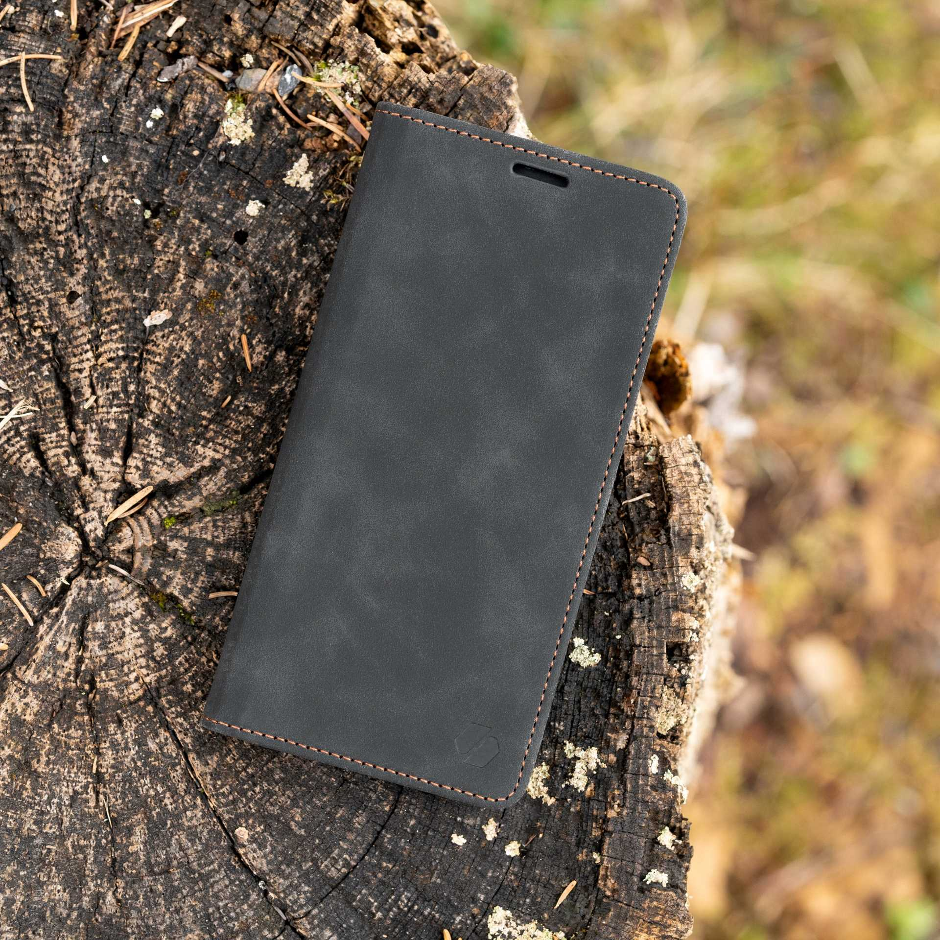 Czarne skórzane etui na telefon na drewnianej powierzchni. Otwarte, pokazujące wnętrze.
