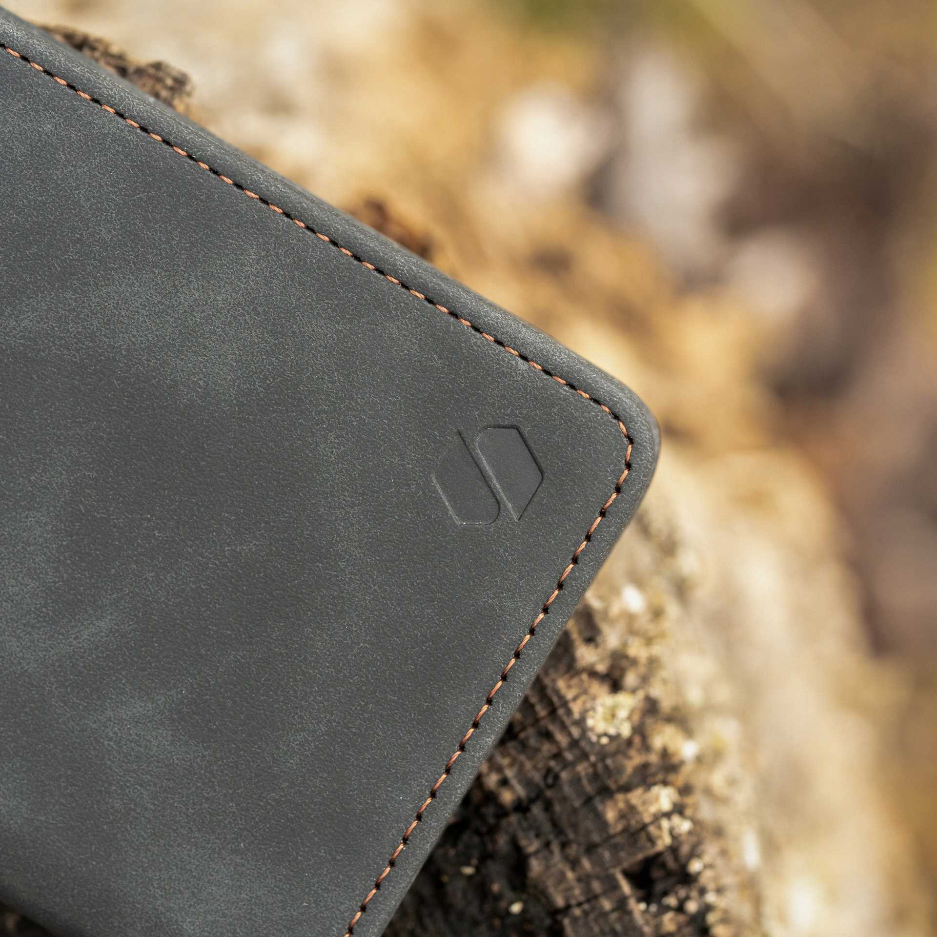 Zbliżenie etui na telefon. Szare etui z pomarańczowymi szwami i logo na drewnianej powierzchni.