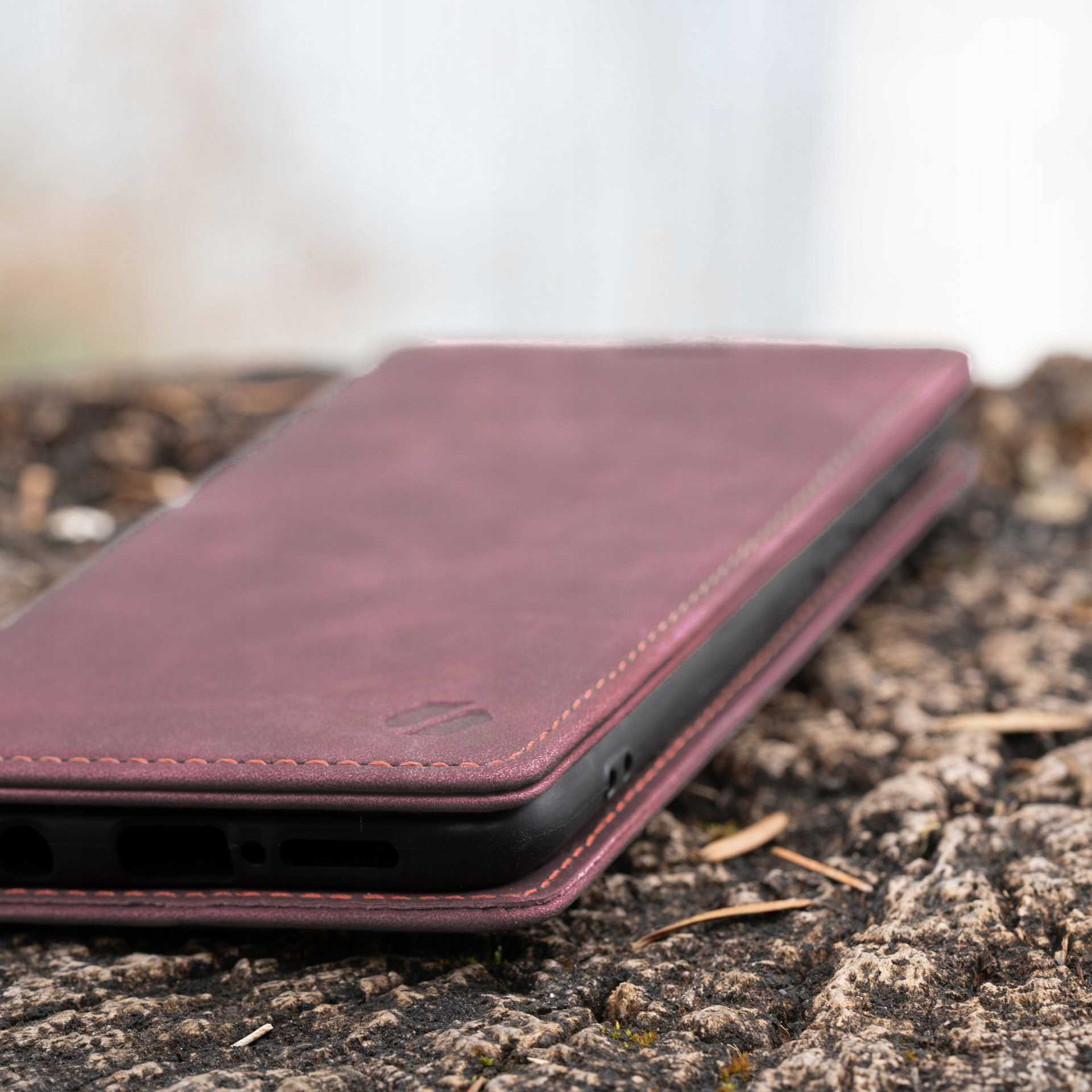 Zamknięte bordowe etui na pniu. Prawdopodobnie skóra.