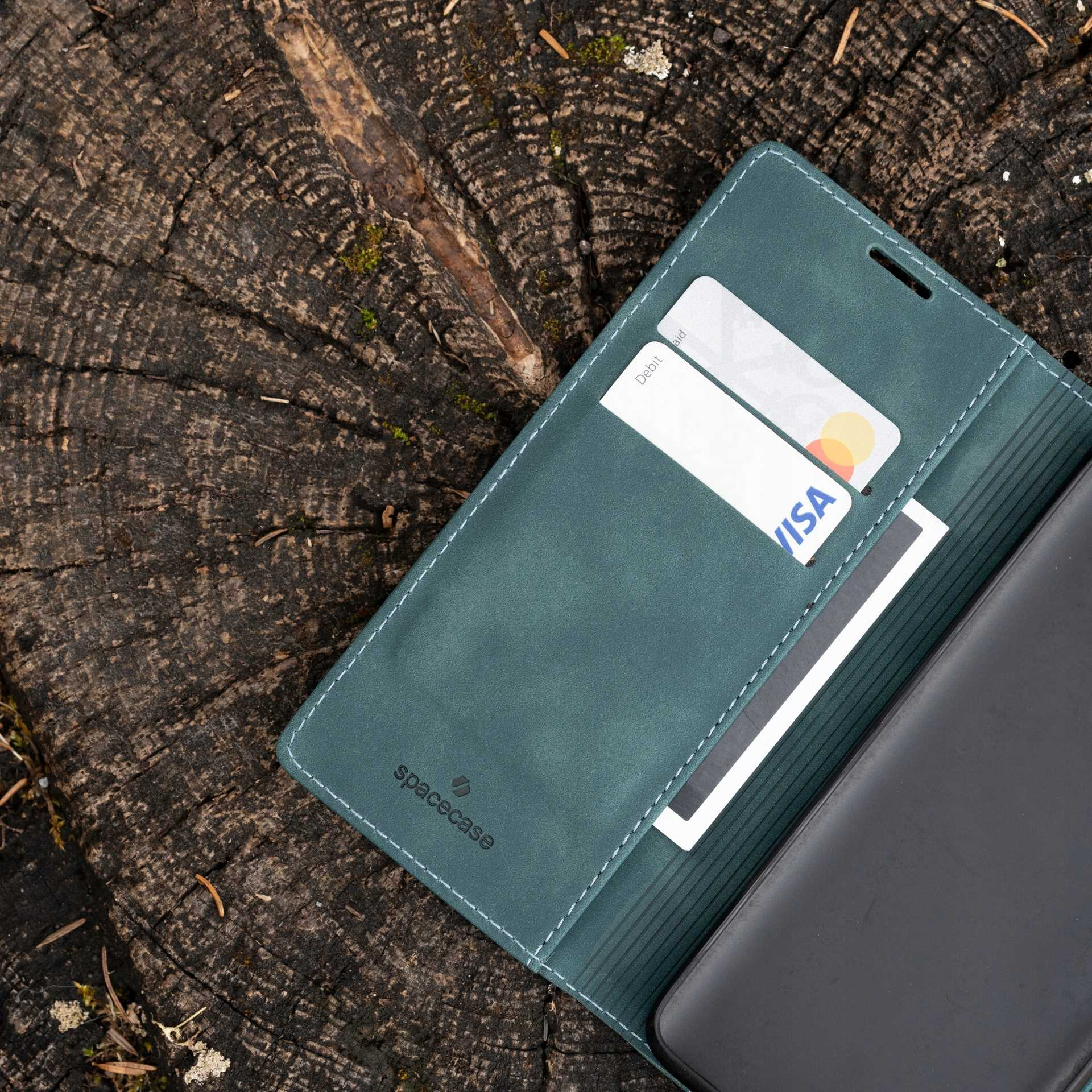Turkusowe etui z miejscami na karty na drewnianej powierzchni, z kartami debetowymi i Visa.