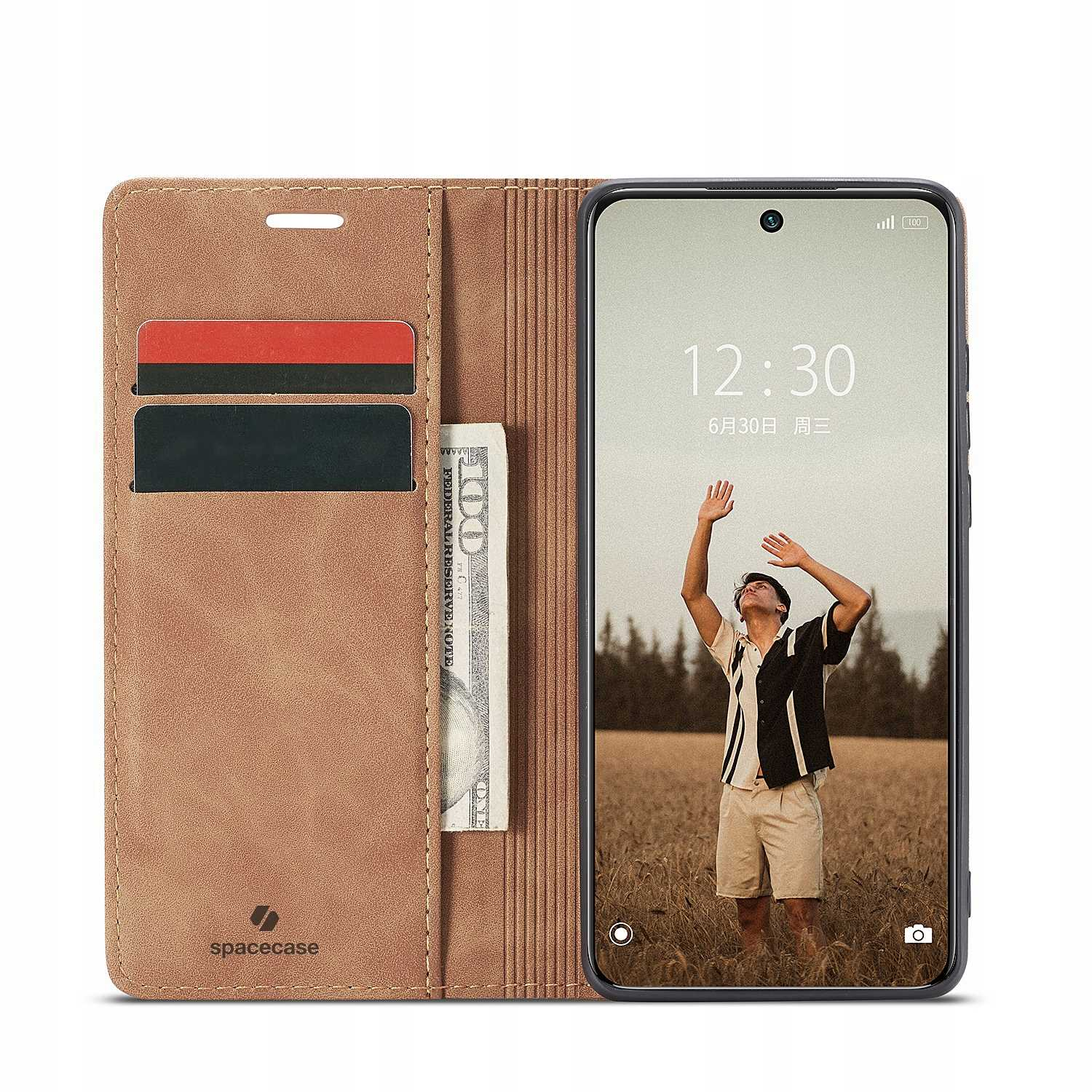 Telefon w skórzanym etui. Osoba na ekranie z podniesionymi rękami. Widoczne karty i pieniądze.