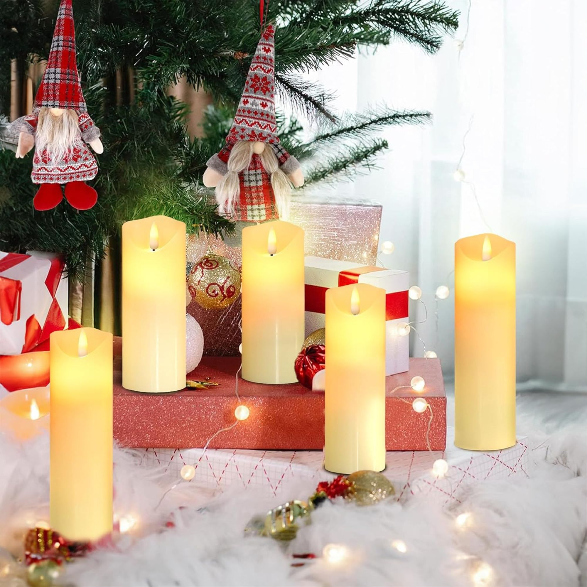 Fünf hohe, leuchtende, zylindrische LED-Kerzen auf einer weißen Oberfläche mit Dekorationen.