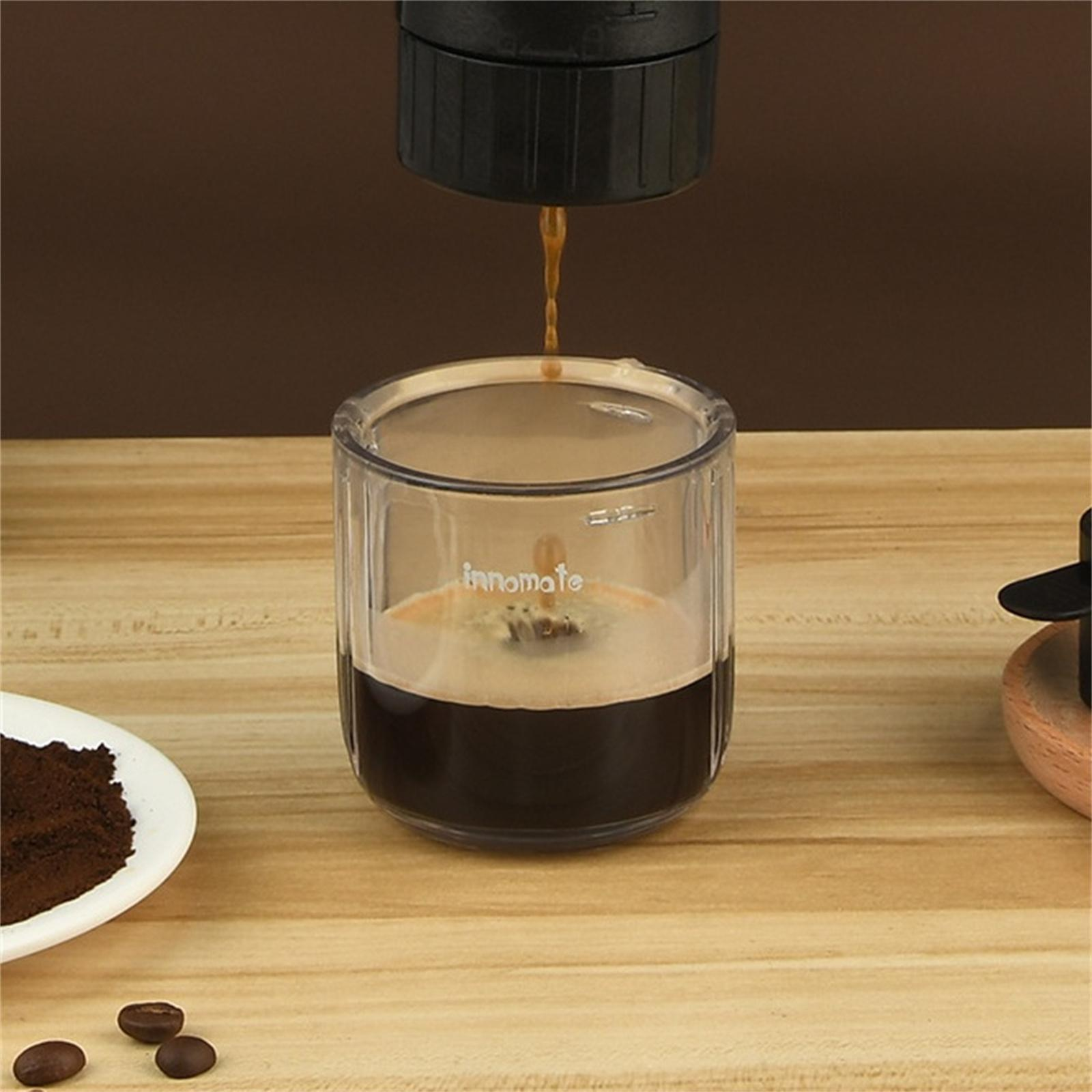 Eine Kaffeemaschine, die Kaffee in ein Glas abgibt. Der Kaffee ist dunkel, mit einer helleren Schicht. Bohnen sind daneben.