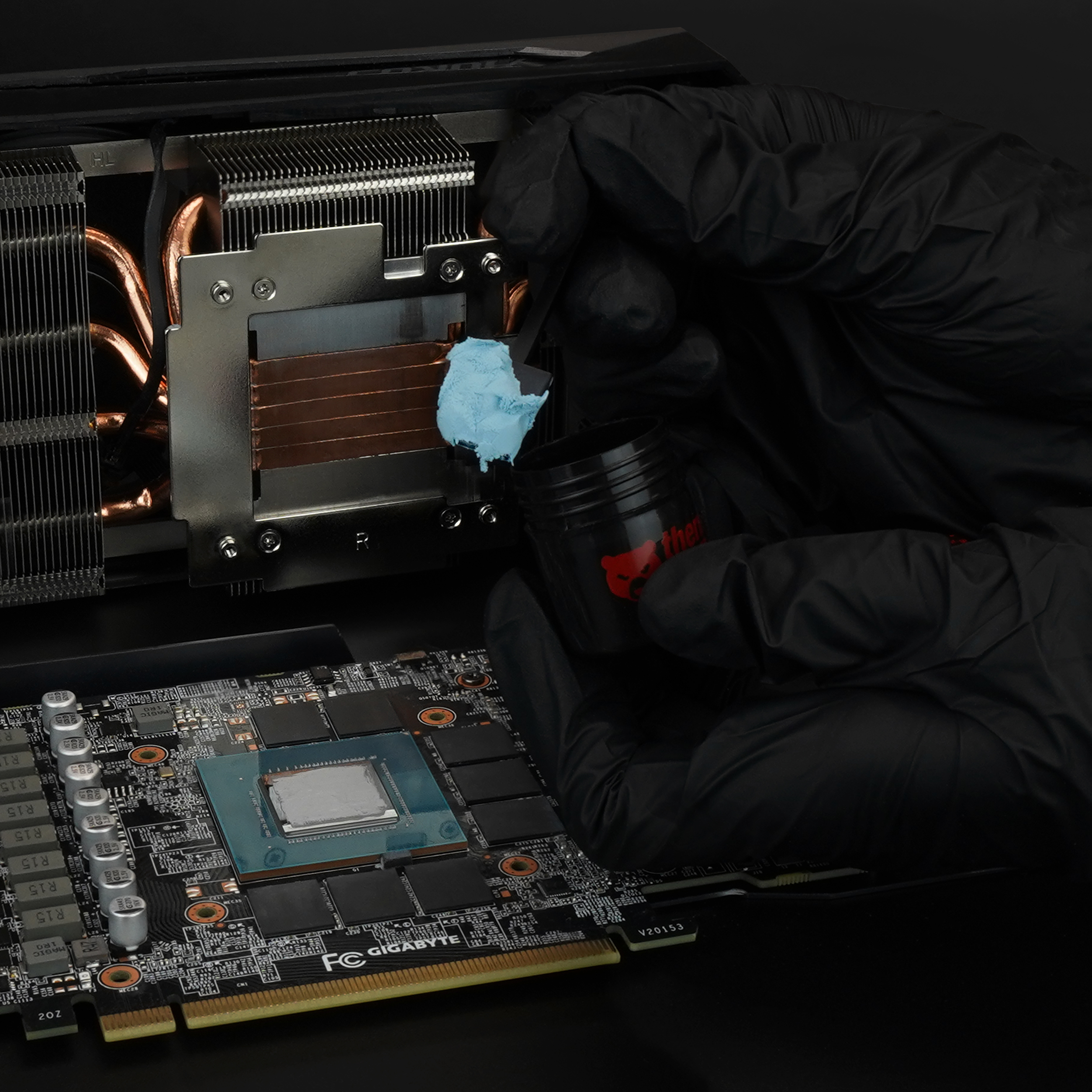 Eine Person in schwarzen Handschuhen trägt Wärmeleitpaste auf einen GPU-Chip auf.