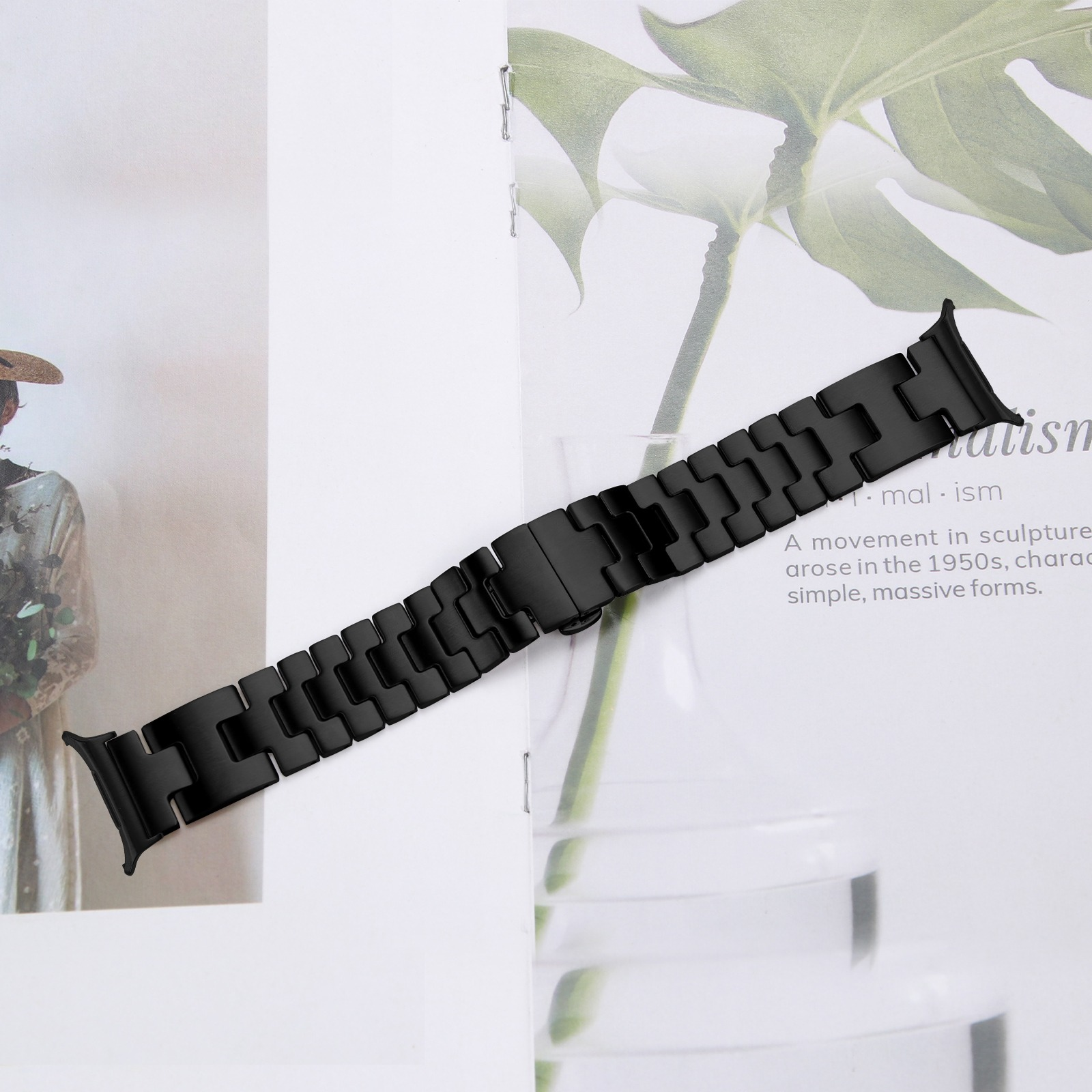 Schwarzes Uhrenarmband liegt auf einer Oberfläche mit einer Pflanze, mit einem Verschluss, isoliert.