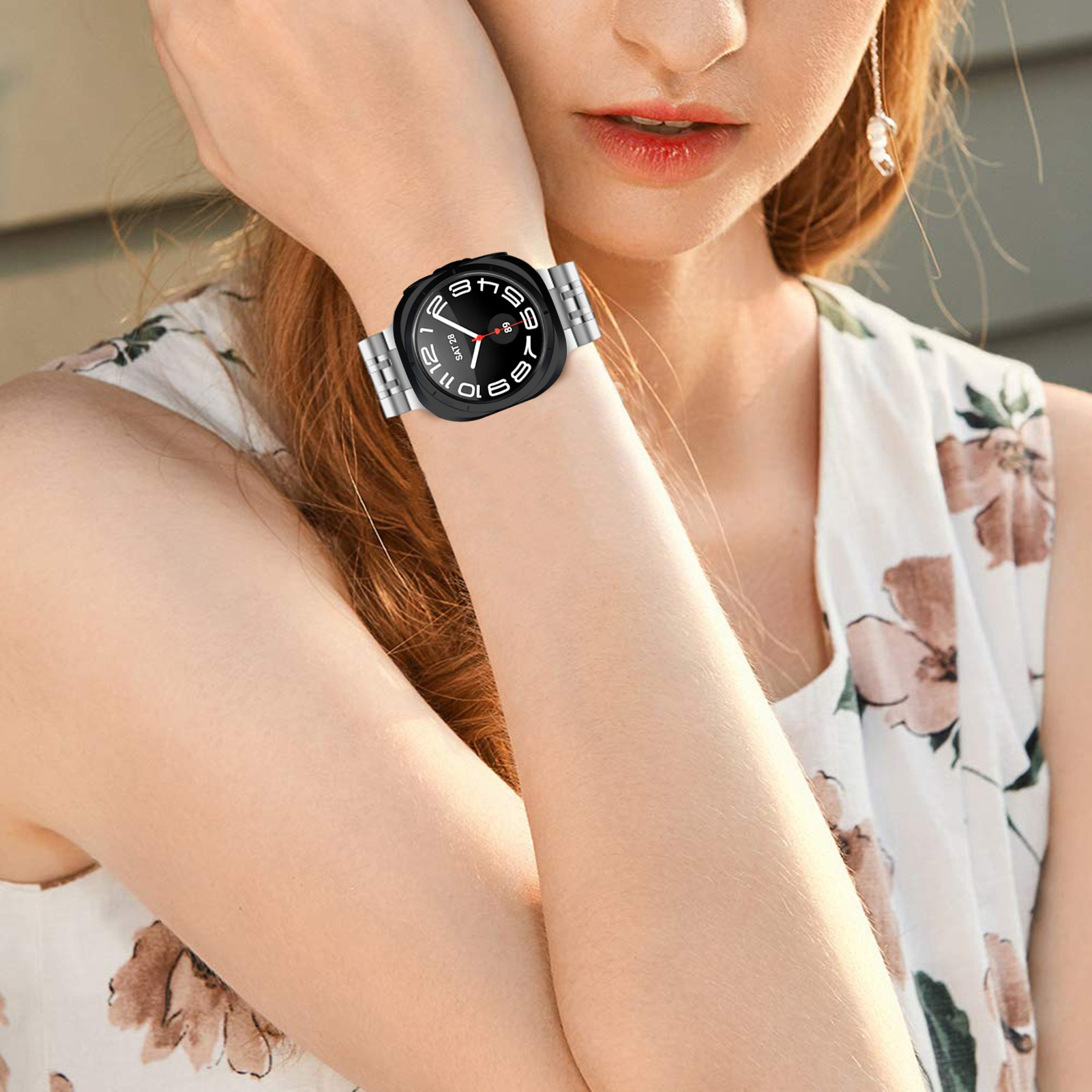 Una donna con un top bianco indossa uno smartwatch nero al polso.