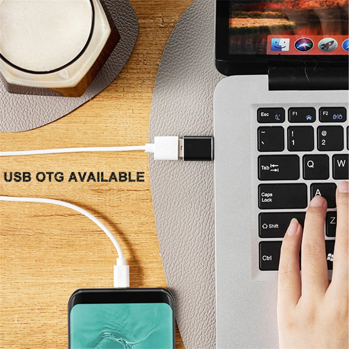 Laptop mit USB-OTG-Kabel, das mit einem Telefon verbunden ist. Graue Oberfläche. Text: USB OTG VERFÜGBAR.