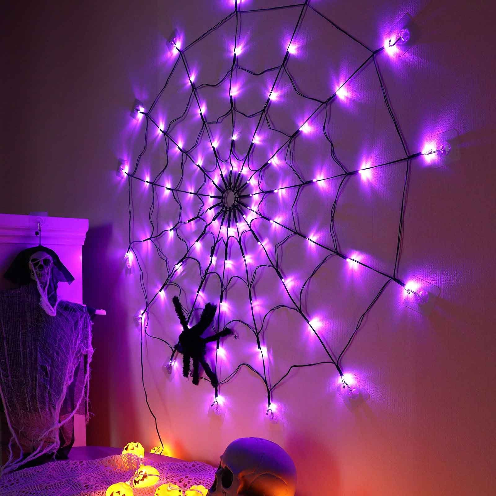 Eine Halloween-Spinnennetzdekoration an der Wand. Ein Totenkopf, Kürbisse und eine Figur links.