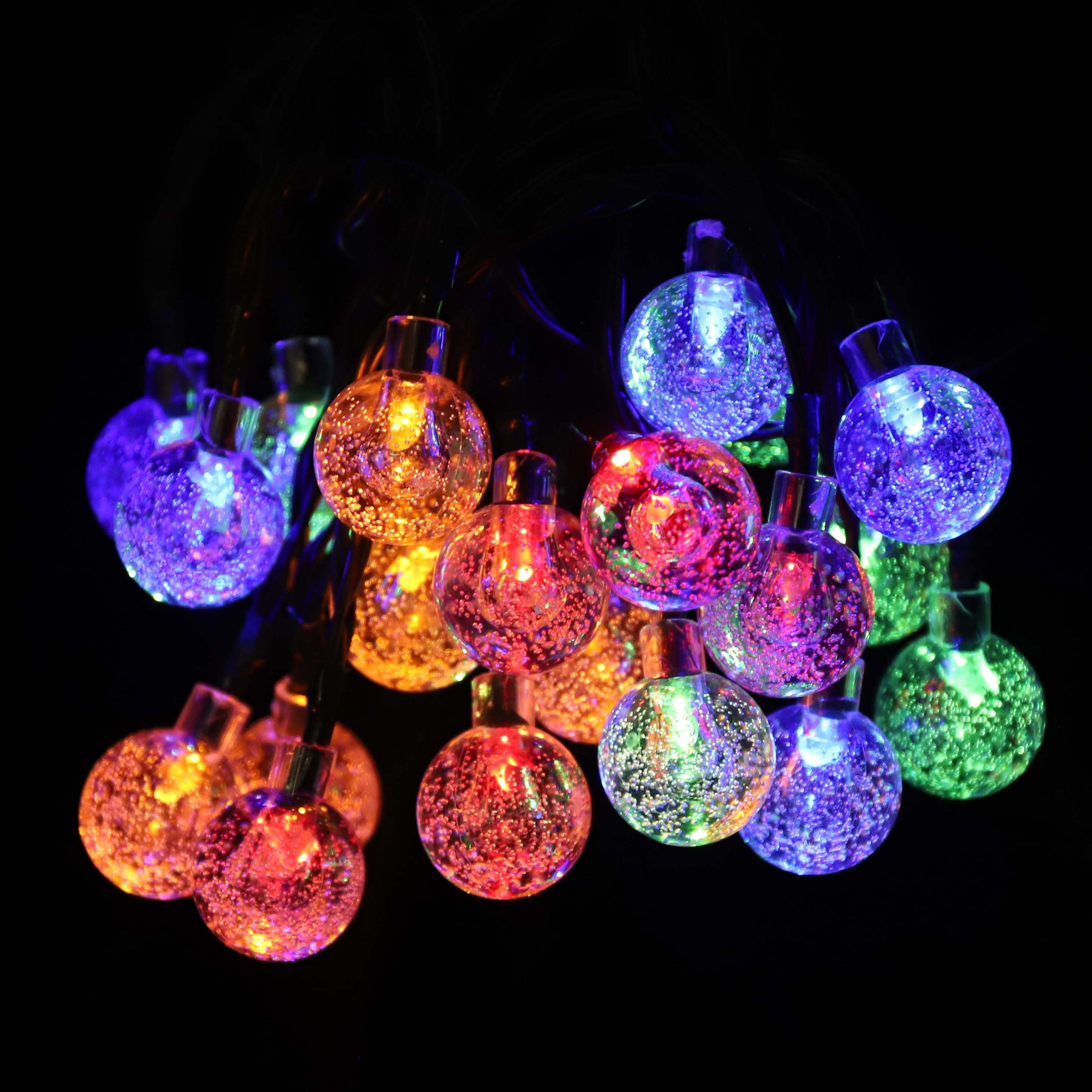 Lichterketten mit bunten, blasenartigen Lichtern. Der Hintergrund ist komplett schwarz.