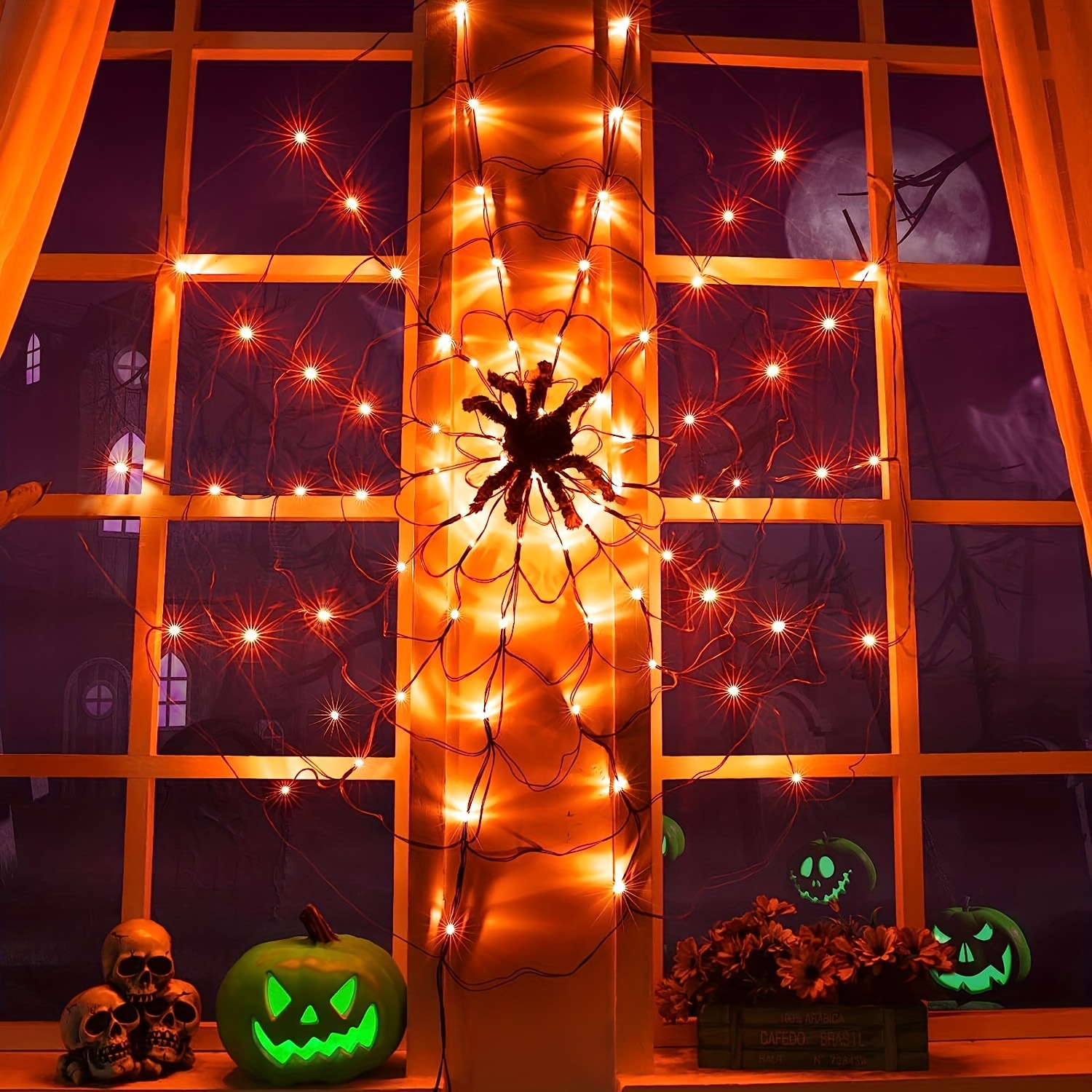 Ein Fenster mit Spinnweben, einer großen Spinne und orangefarbenen Lichtern.