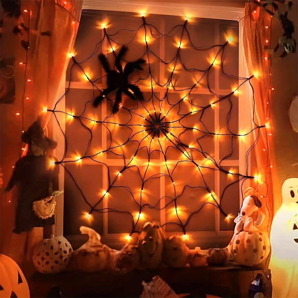Eine Halloween-Fensterdekoration mit Spinnennetz, Lichtern und Kürbissen. Eine Hexe und ein Geist sind vorhanden.