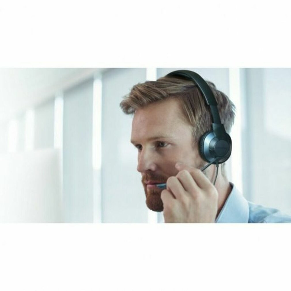 Mężczyzna w słuchawkach z mikrofonem. Ma brodę i patrzy w lewo.