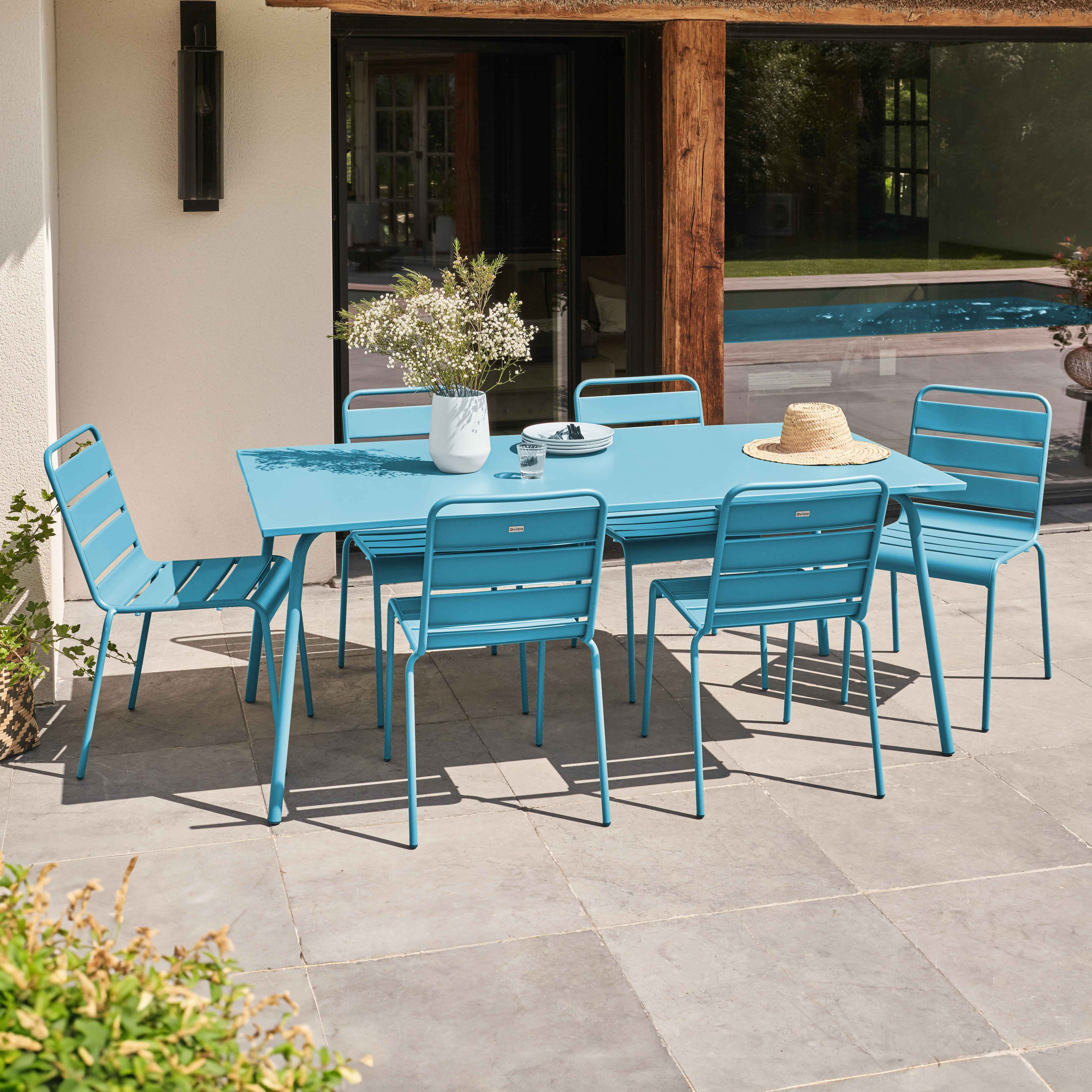 Ein blaues Ess-Set im Freien auf einer Terrasse mit Pflanzen.