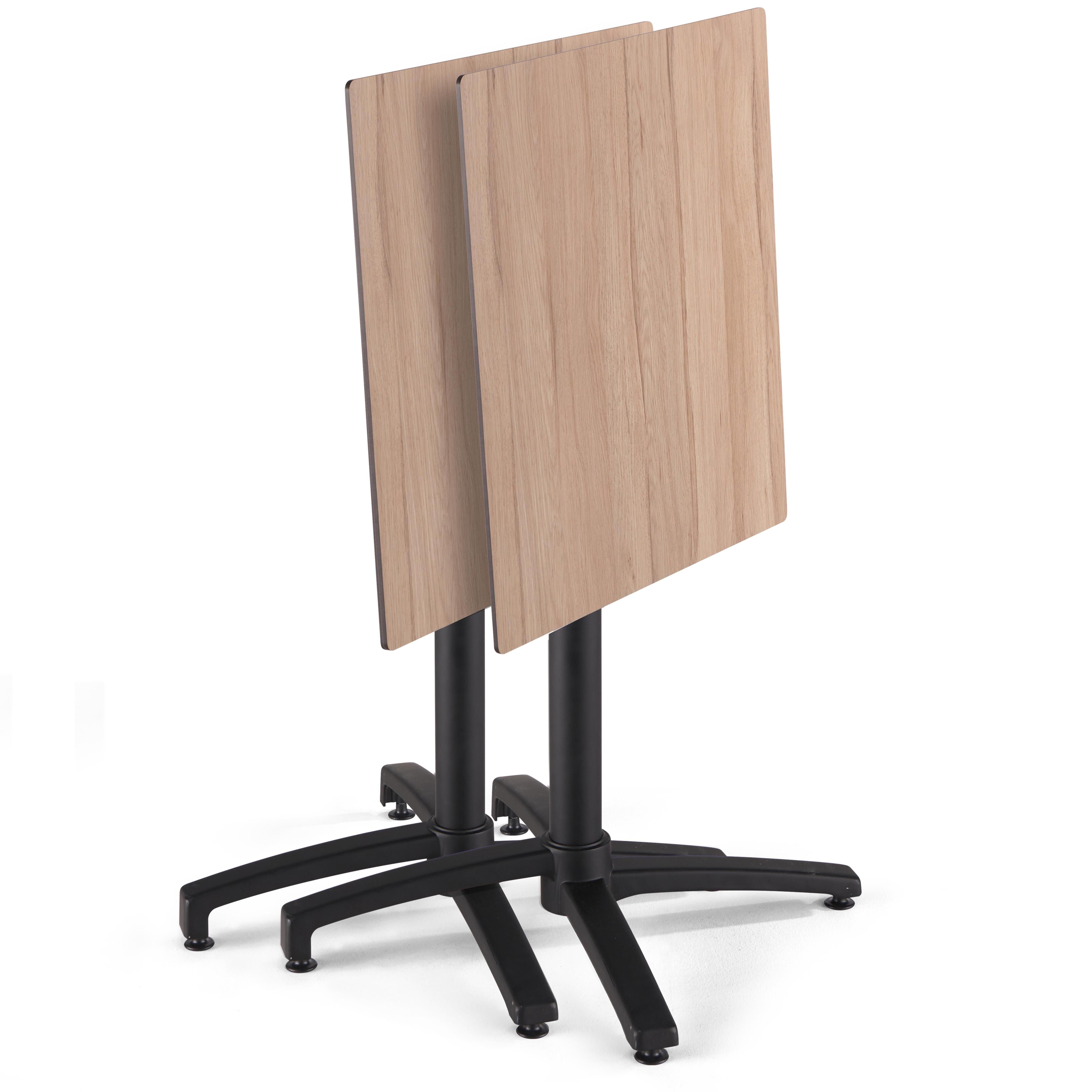 Ein quadratischer Tisch mit hellbrauner Holzmaserung. Der Tisch hat ein schwarzes Gestell mit vier Füßen.