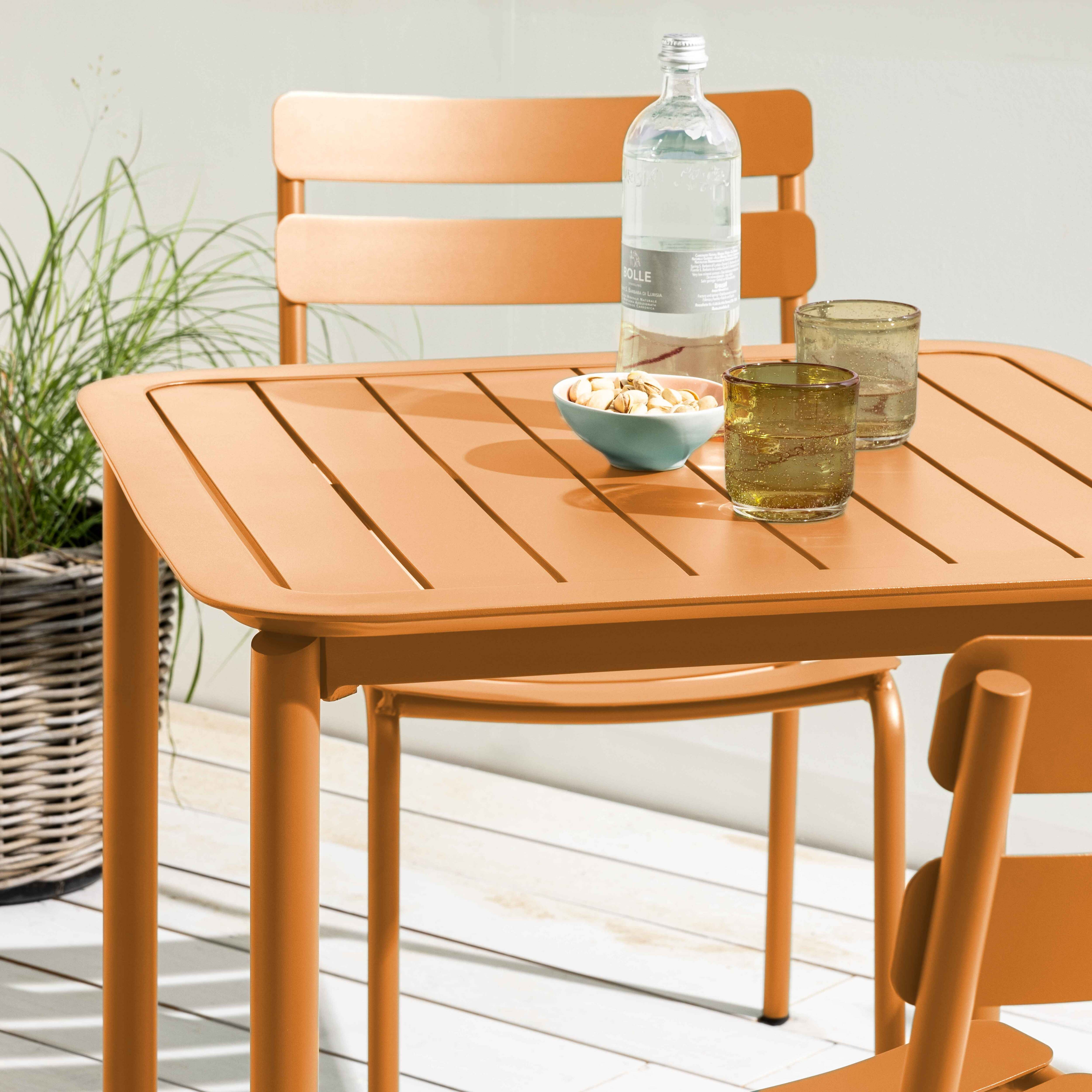 Orangener Tisch mit Gläsern und Snacks sowie einem Weidenkorb.