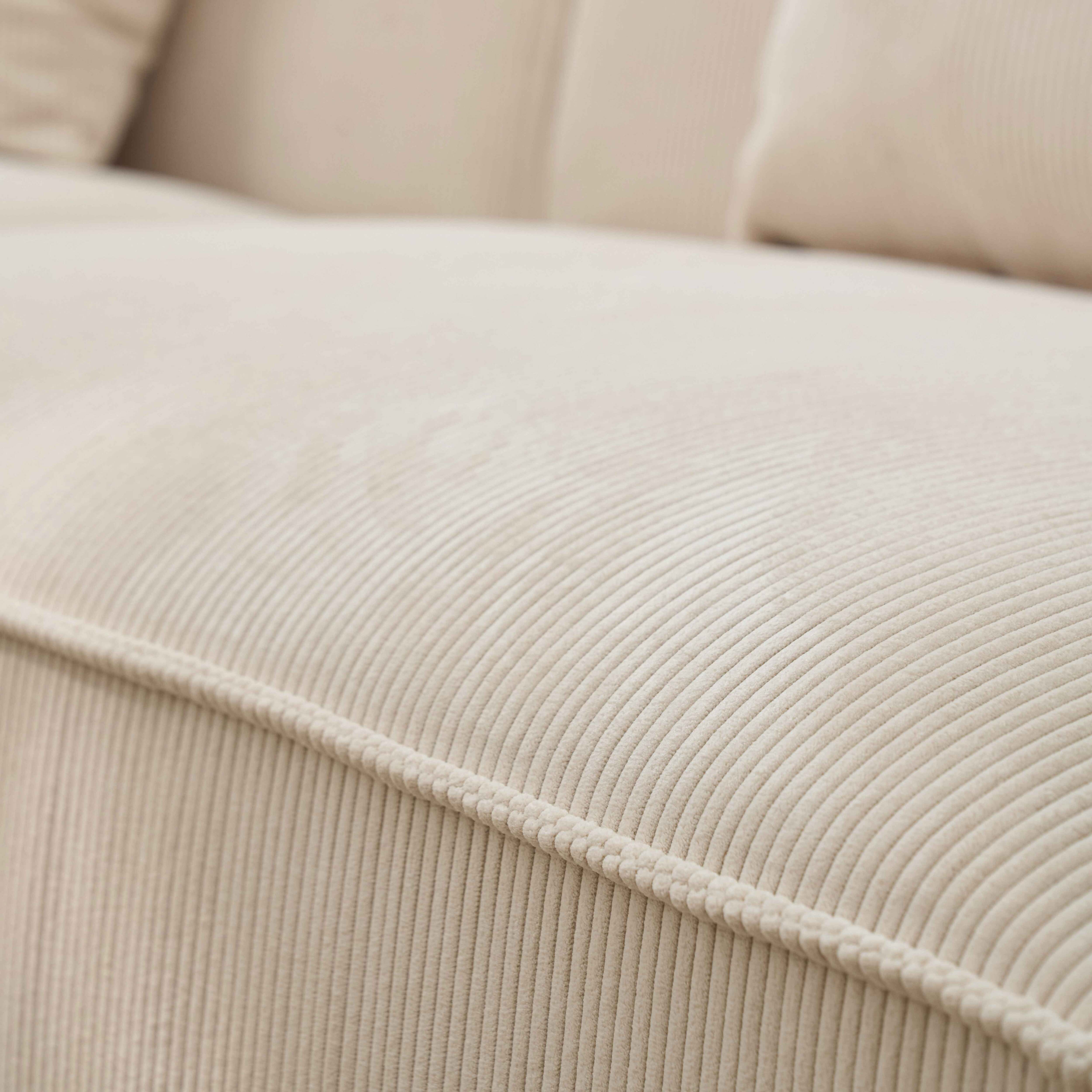 Eine Nahaufnahme zeigt ein hellbeige Cordsofa, dessen Stoff erhöhte, parallele Rippen aufweist.