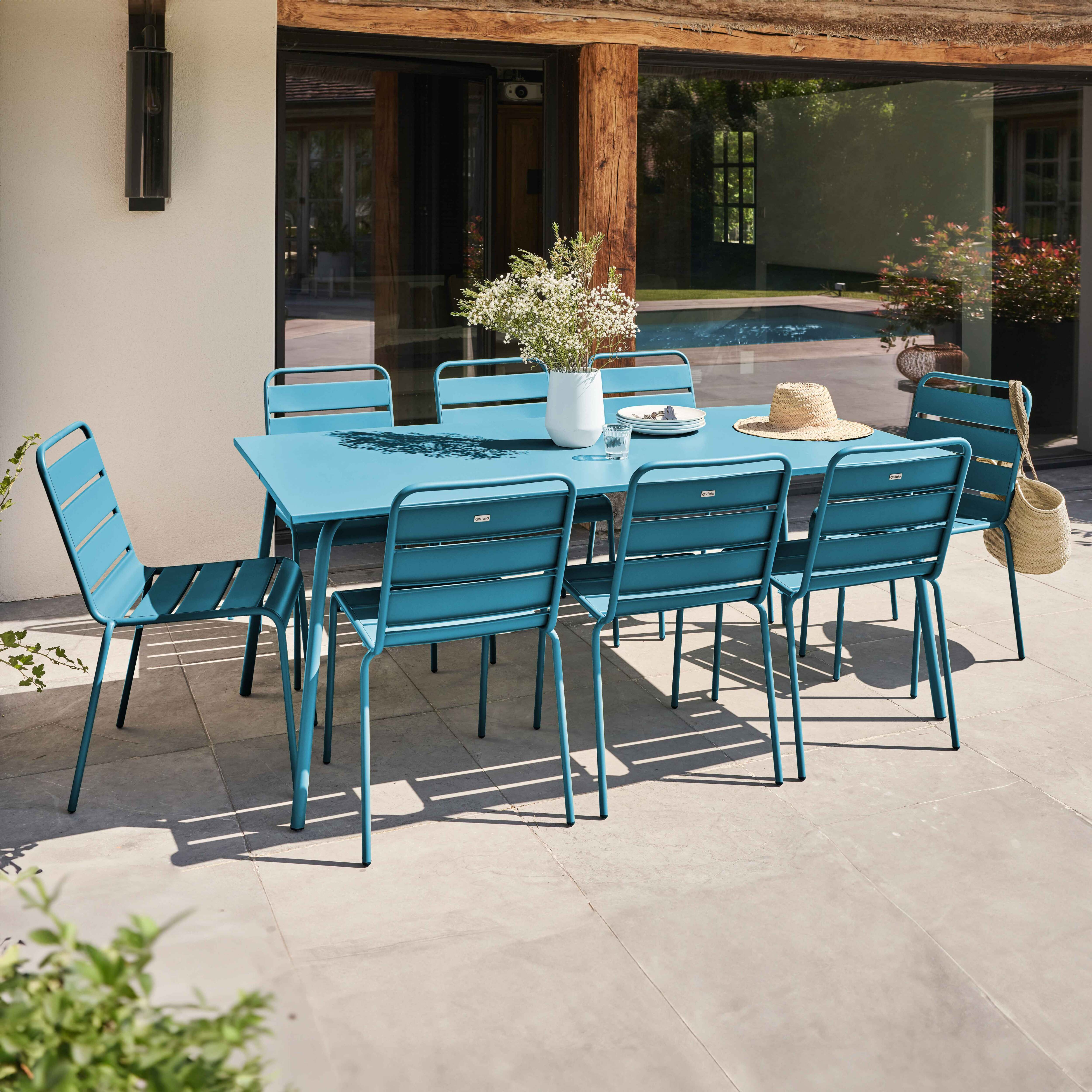 Ein Ess-Set im Freien mit einem blauen Tisch und sechs blauen Stühlen.