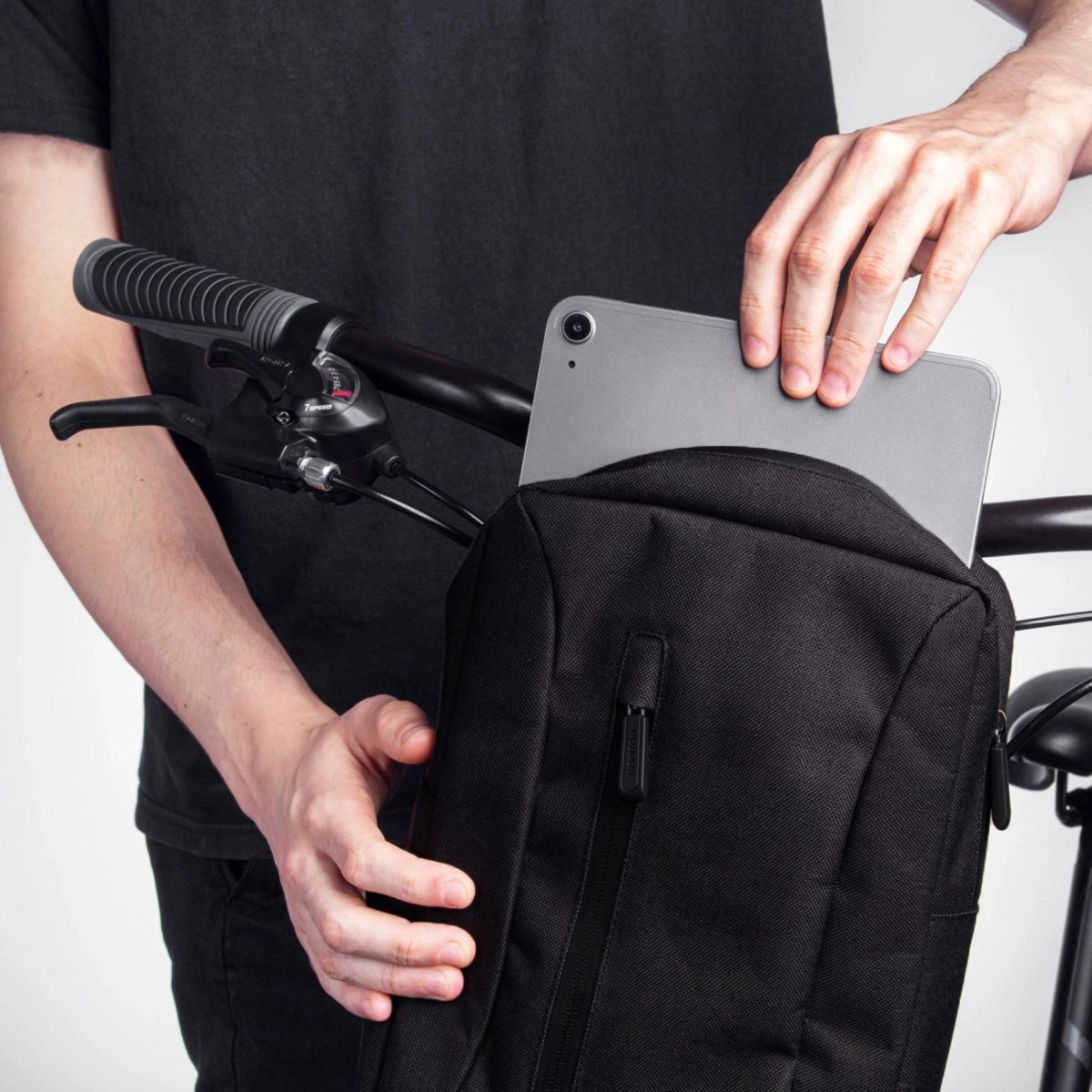 Osoba wkładająca tablet do czarnej torby przymocowanej do roweru.