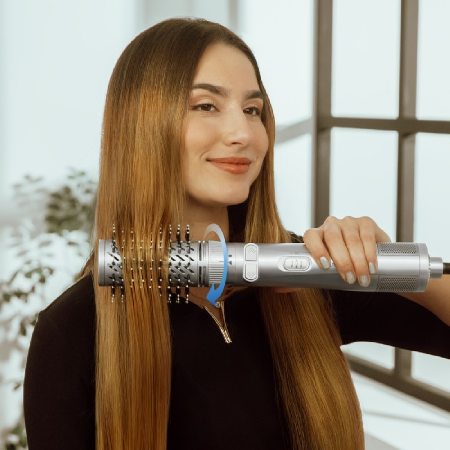Una donna tiene in mano una spazzola per capelli argentata, dimostrando il suo utilizzo sui suoi lunghi capelli biondi.