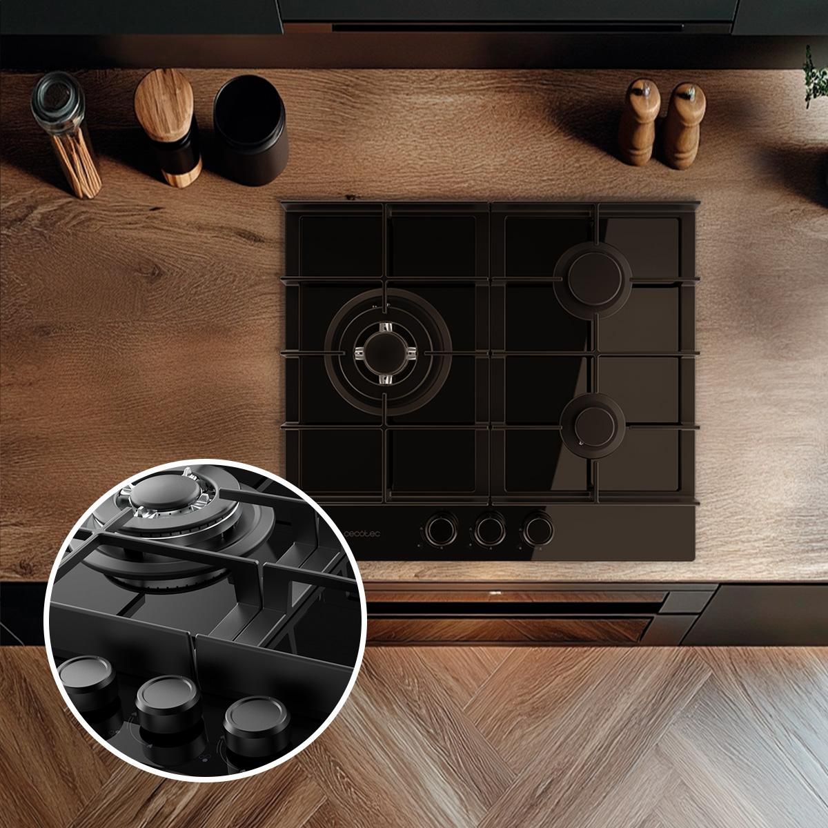 Czarna płyta gazowa na drewnianej powierzchni. Widoczne pokrętła i palniki. Akcesoria w tle.