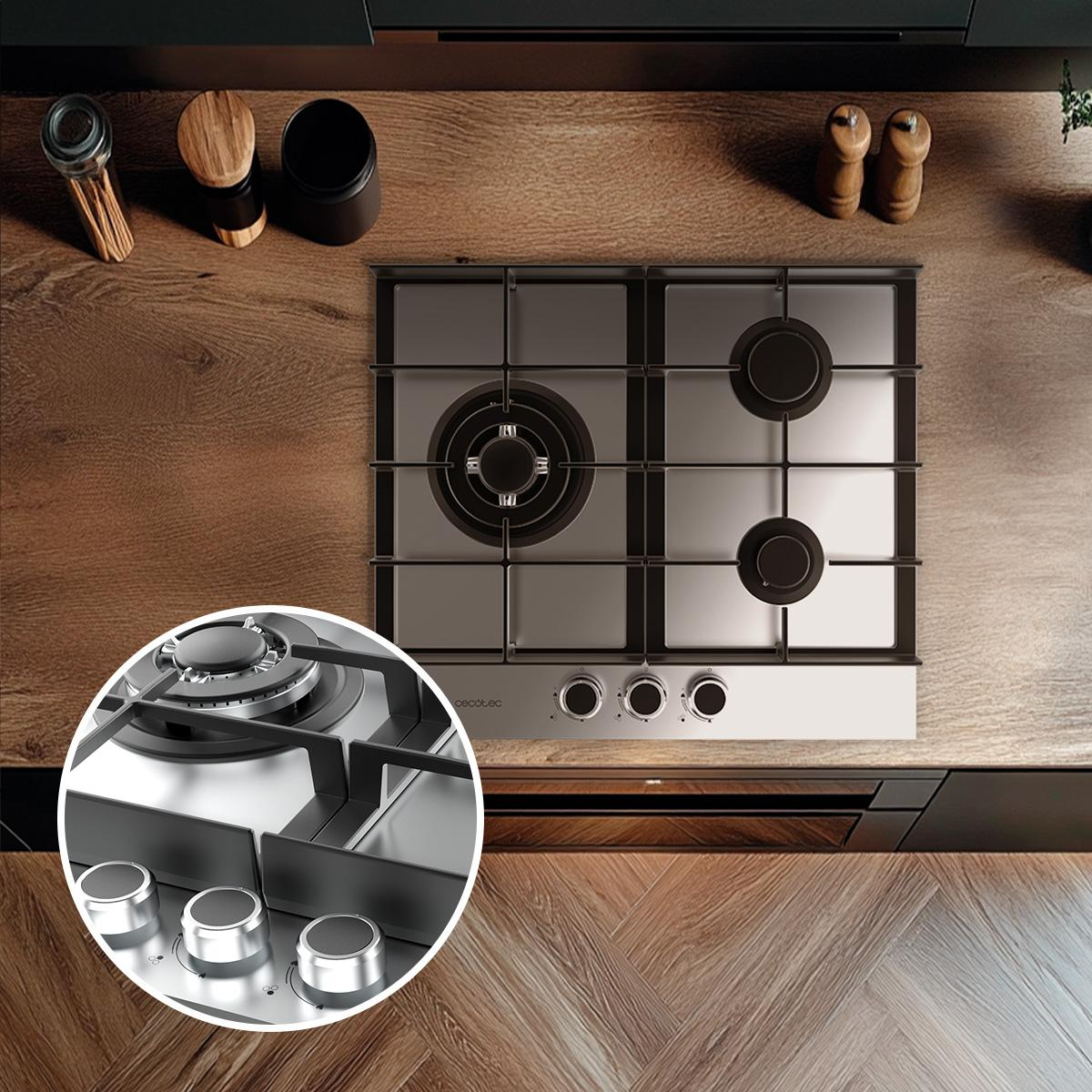 Płyta ze stali nierdzewnej na drewnianej powierzchni. Widoczne pokrętła i palniki. Akcesoria w tle.