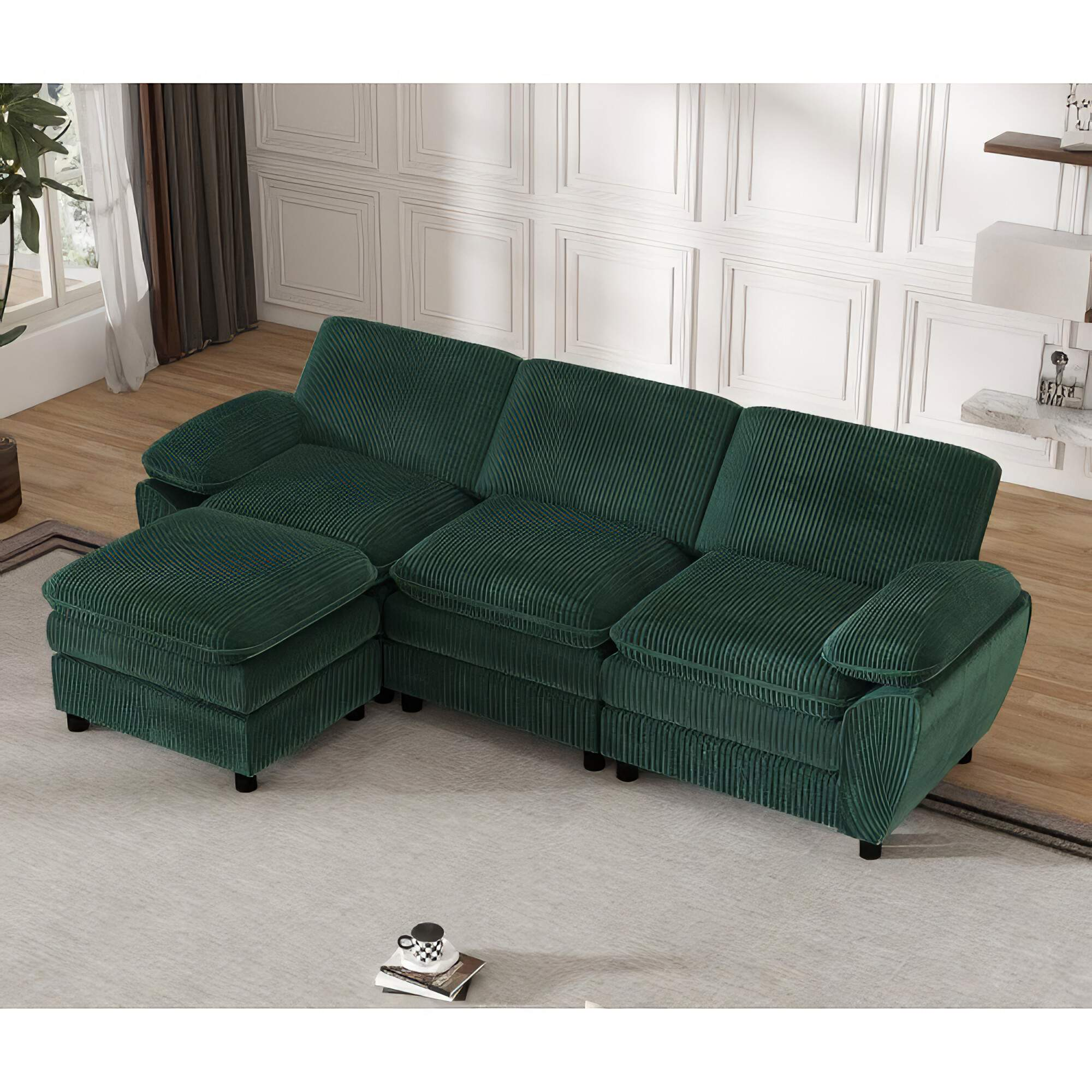 Ein großes grünes Cordsofa in einem Wohnzimmer. Es hat eine Ottomane links.