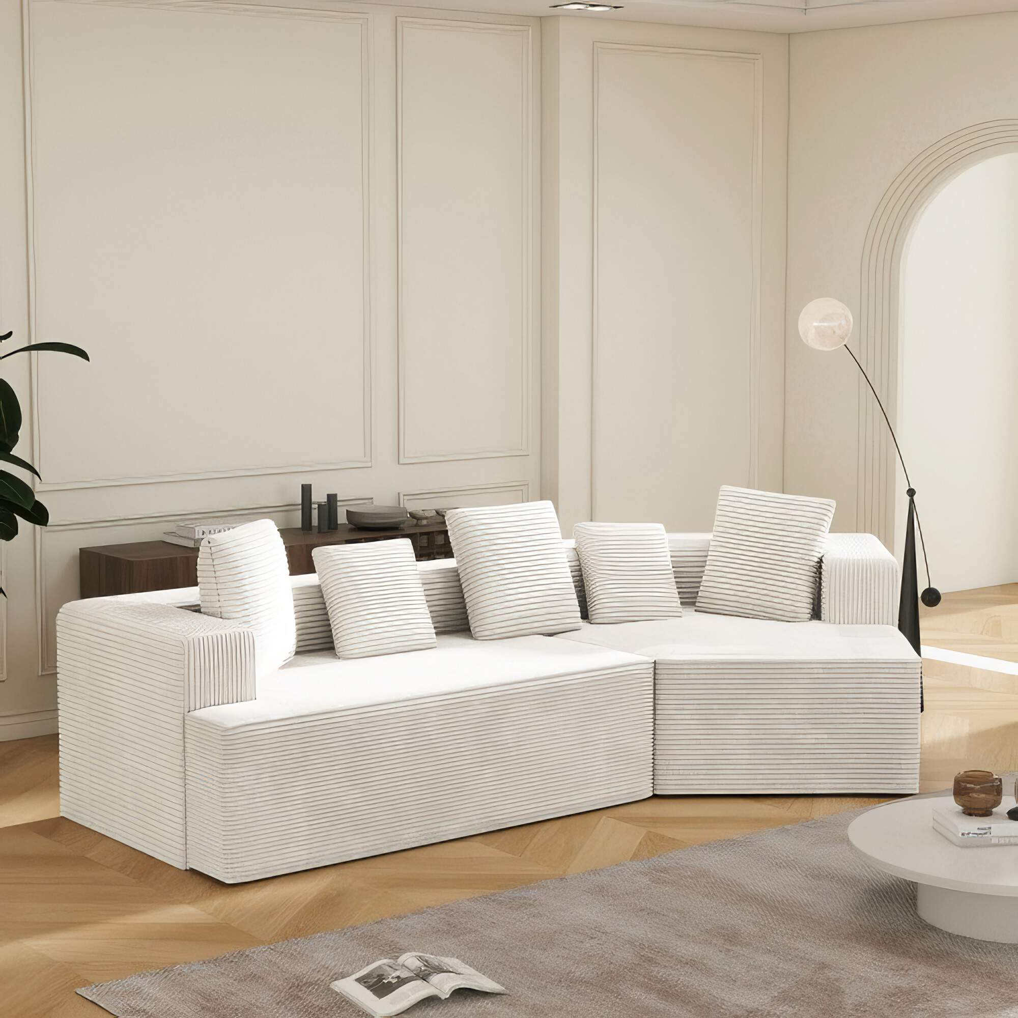 Weißes Ecksofa in einem modernen Raum. Das Sofa hat Kissen und steht auf einem Holzboden.
