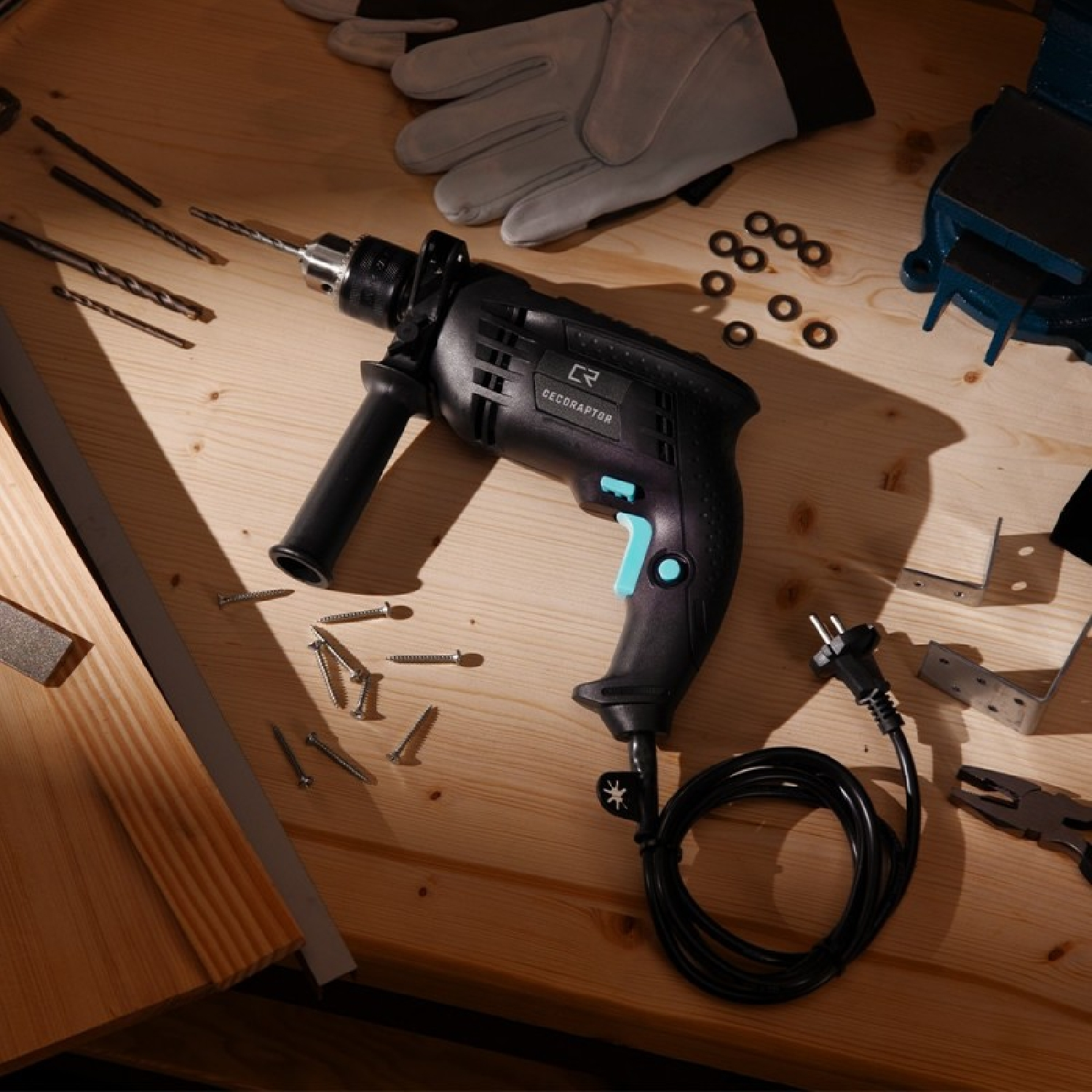 Schwarze Bohrmaschine auf Holztisch mit Schrauben und Werkzeugen. Handschuhe und andere Werkzeuge sind vorhanden.