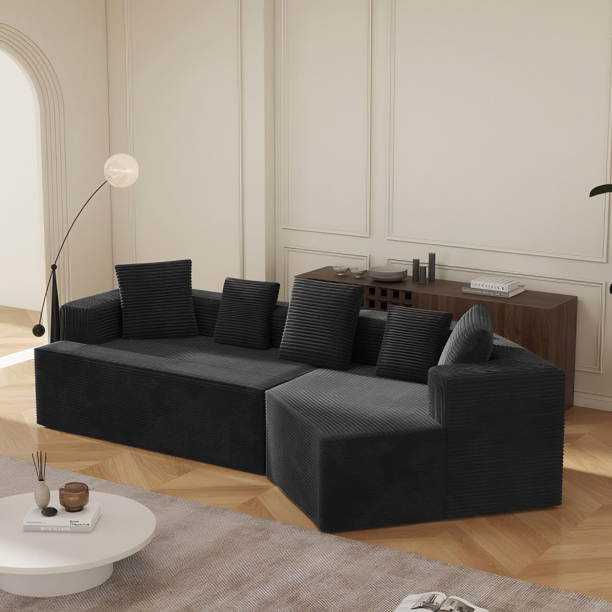 Ein modernes schwarzes Ecksofa mit Kissen in einem neutralen Raum.