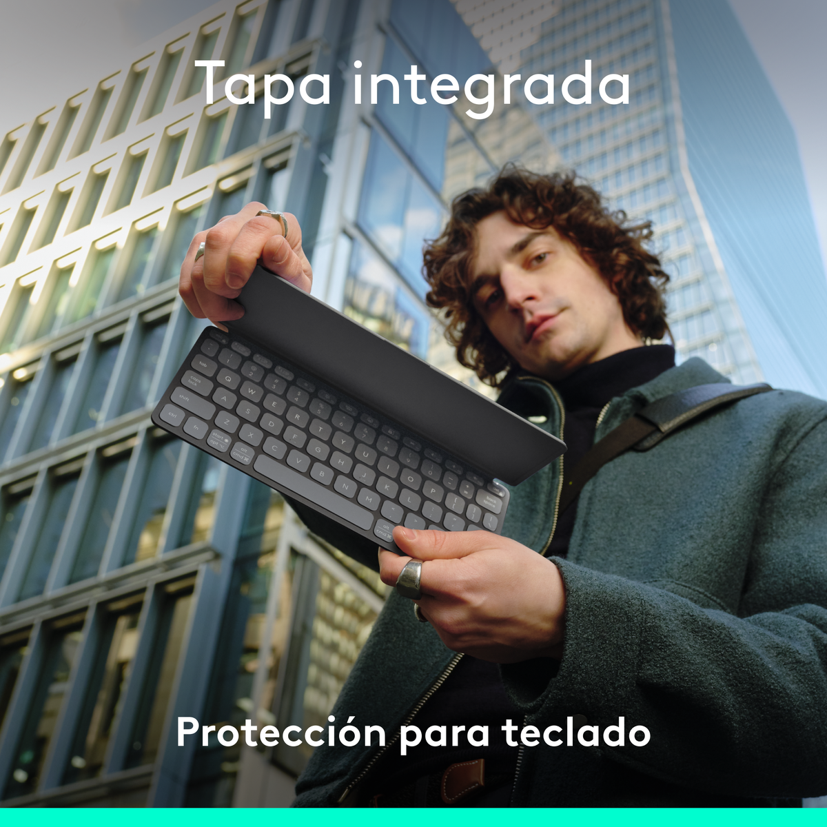 Un hombre sostiene un teclado con una cubierta frente a un edificio alto. El texto dice 'Tapa integrada' y 'Proteccion para teclado'.