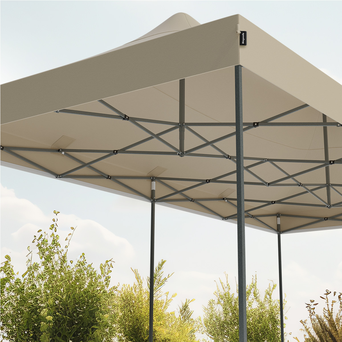 Close-up view of a beige tent's top, supported by black poles, set against a blue sky with some greenery.