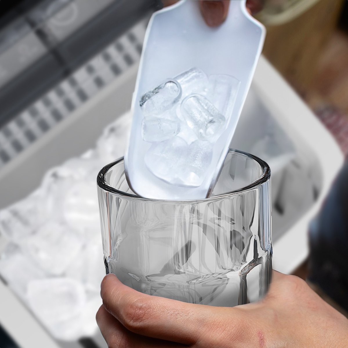 Hands using a scoop to put ice cubes into a glass.