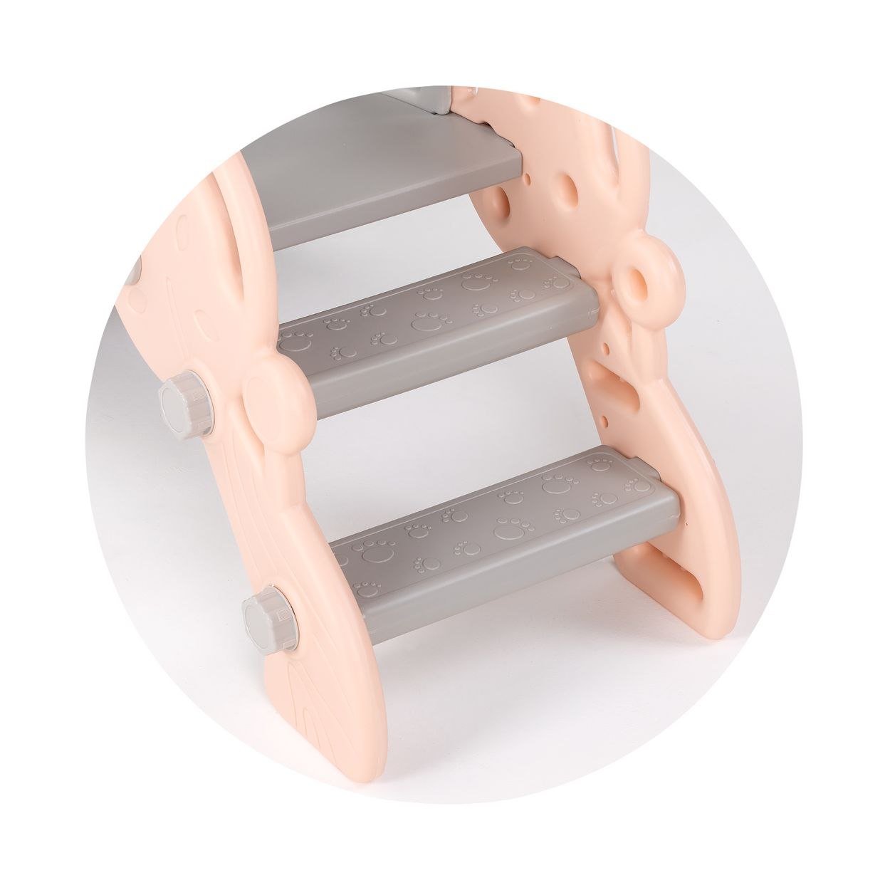 Nahaufnahme der Treppe einer rosa Rutsche. Graue Stufen mit gepunkteten Texturen sind vor einem rosa, abgerundeten Träger sichtbar.