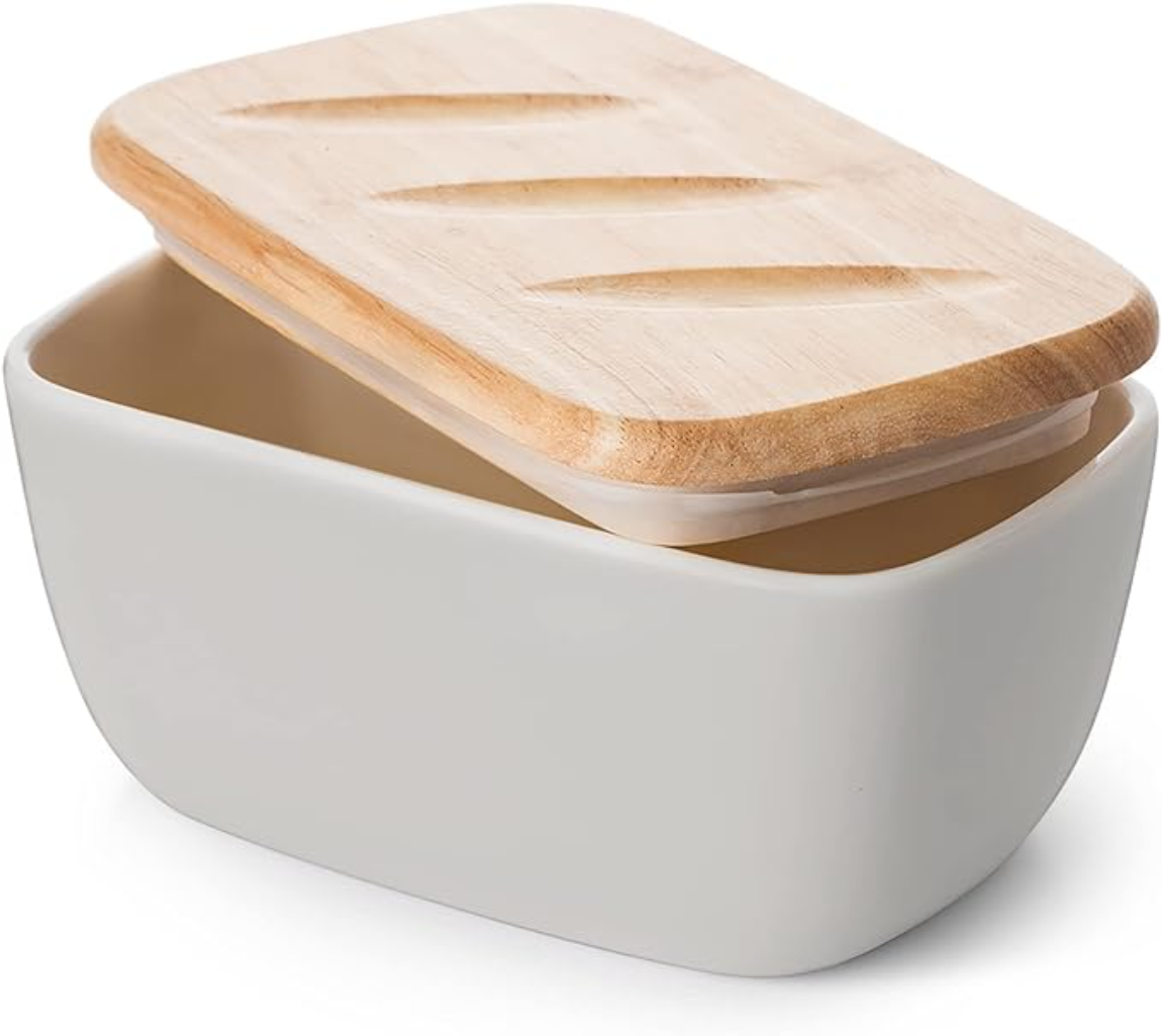 Una burriera bianca con coperchio in legno, vista angolata, con burriera aperta.