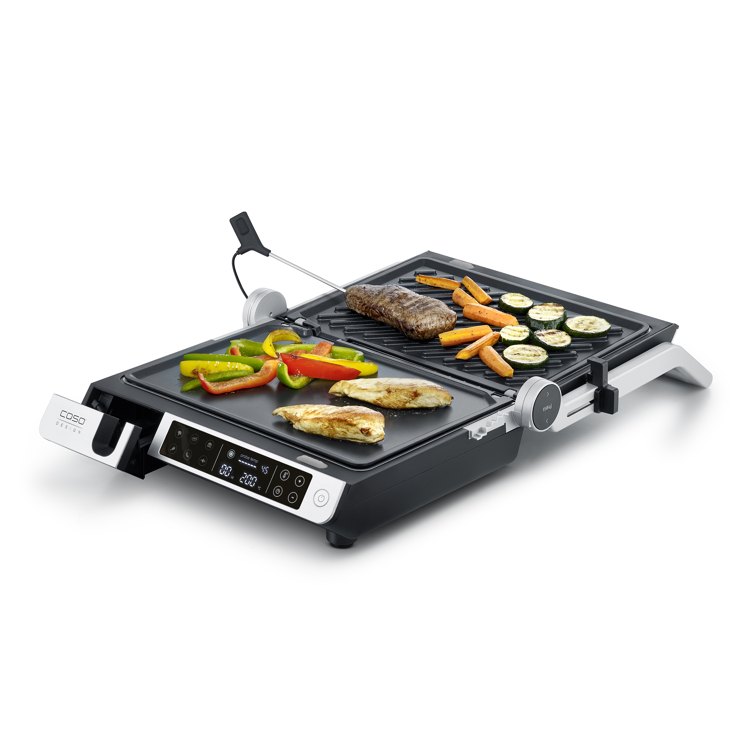 Ein elektrischer Grill mit Speisen, darunter Gemüse, Steak und Hähnchen, auf einer weißen Oberfläche.