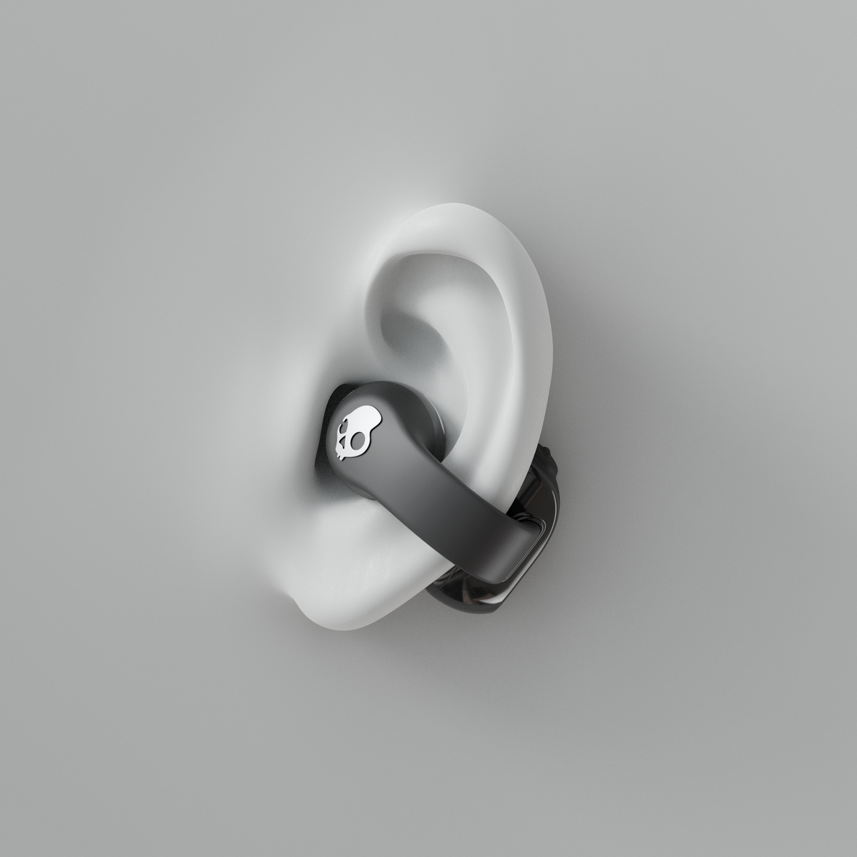 Auricolare in un orecchio su sfondo grigio. L'auricolare ha un logo a teschio.
