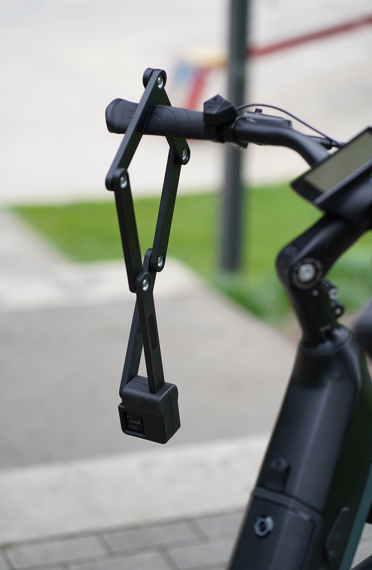 Schwarzes Fahrradschloss am Fahrradlenker befestigt. Das Schloss ist gefaltet.