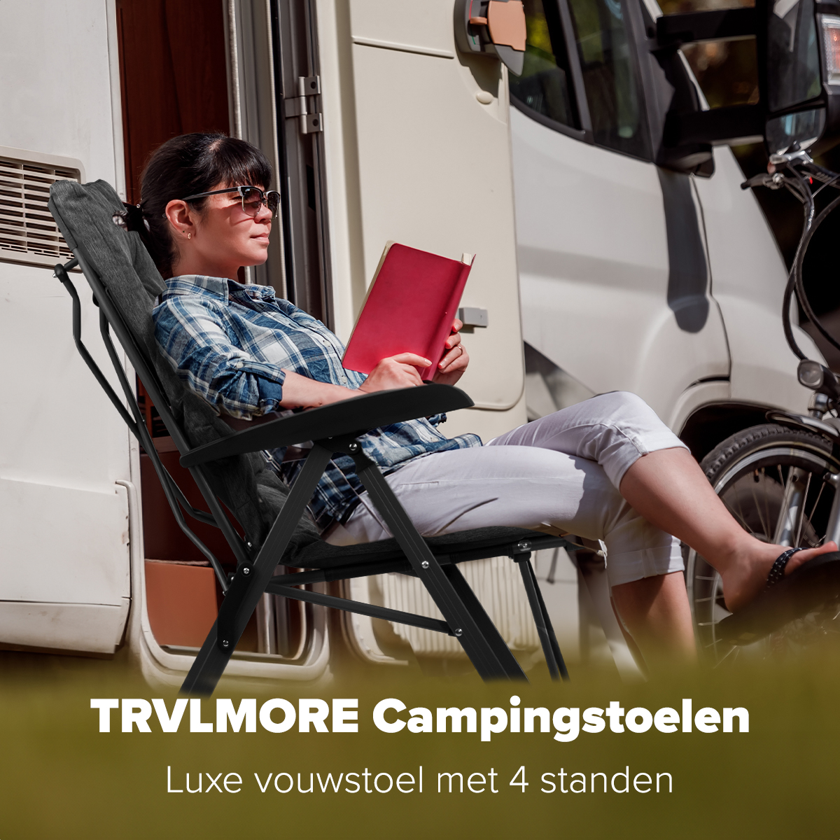 Woman in sunglasses reading a book, sitting in a black camping chair. A camper is in the background.