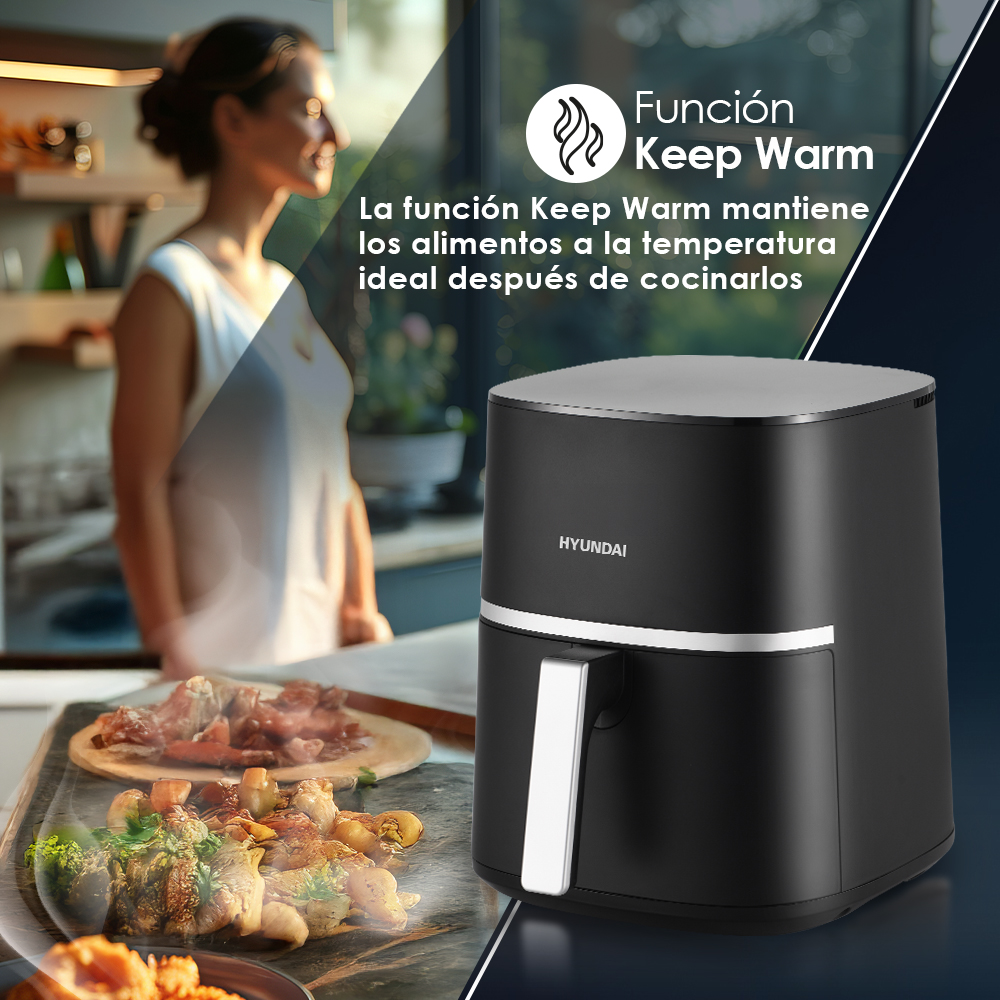 Freidora de aire negra en una encimera de cocina con una mujer al fondo y comida cocinada en primer plano.