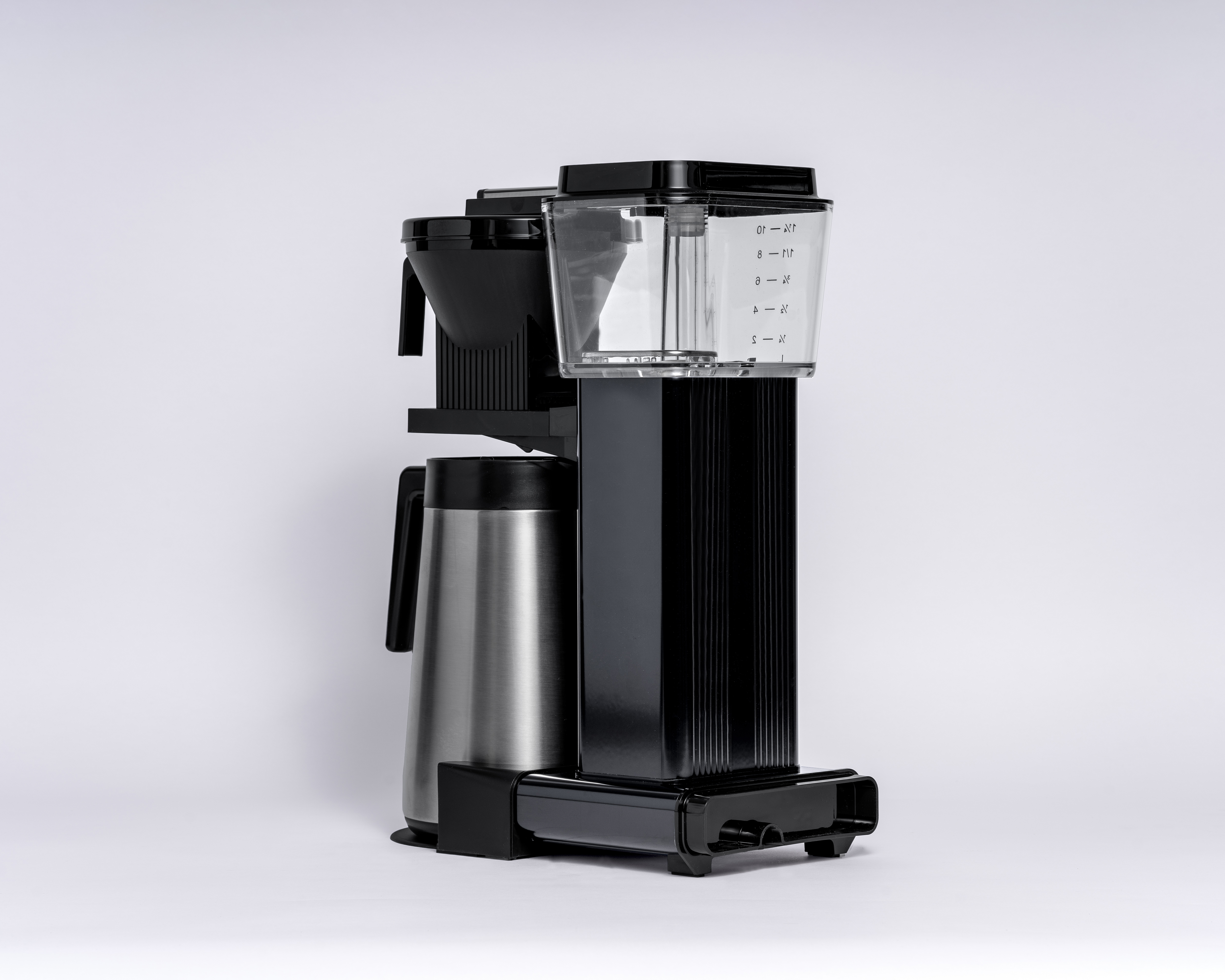 Czarny ekspres do kawy z karafką i przezroczystym zbiornikiem na wodę. Widok z boku, na białym tle.