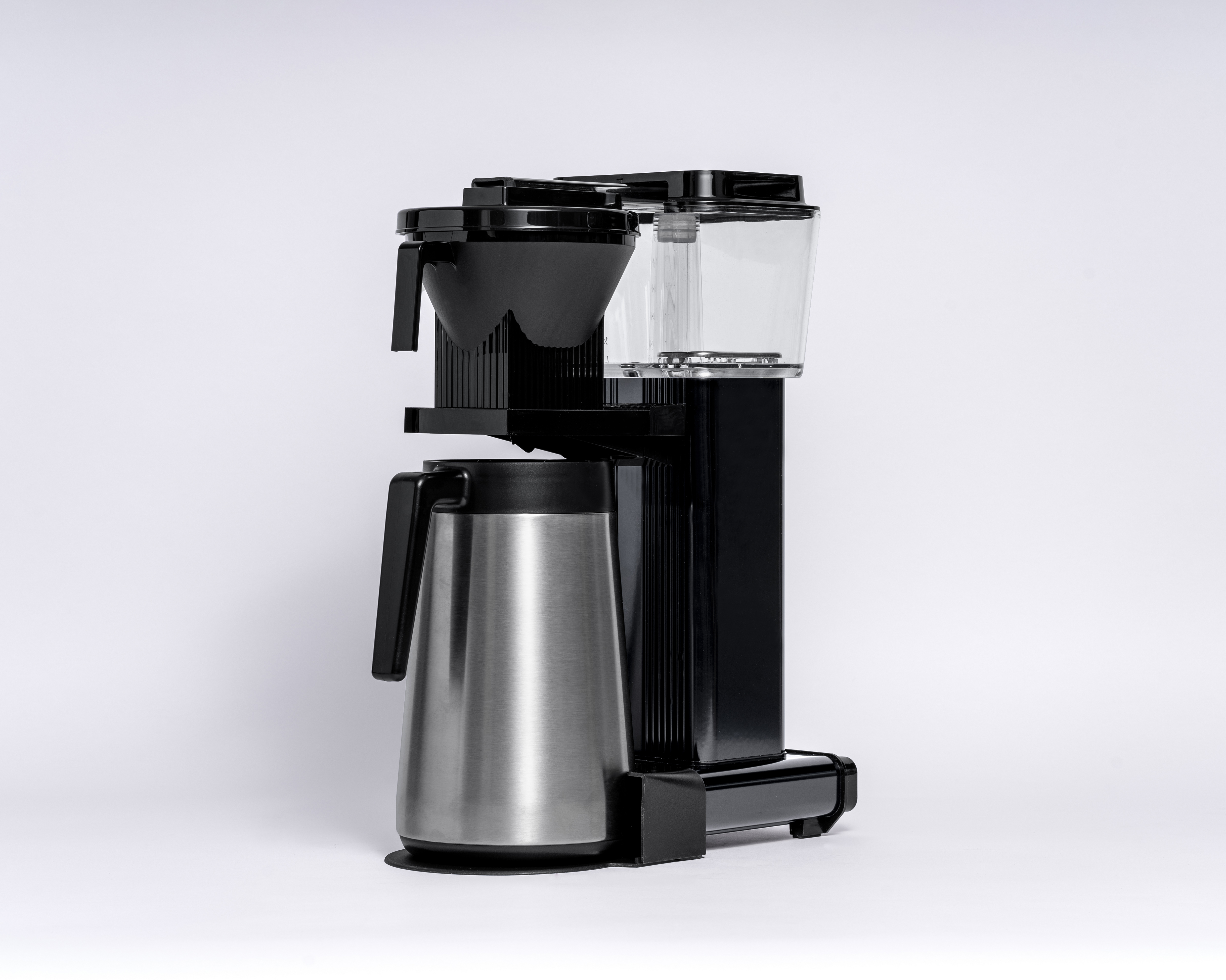 Czarny i srebrny ekspres do kawy z karafką na białym tle. Ekspres do kawy ma nowoczesny design.