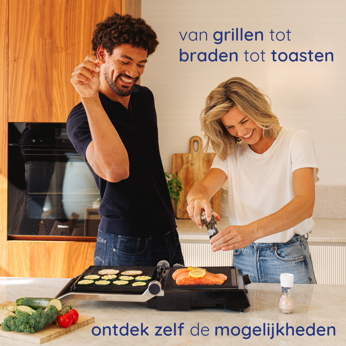 A man and woman are preparing food on a grill. Vegetables, salmon, and salt are on the grill. They are smiling.