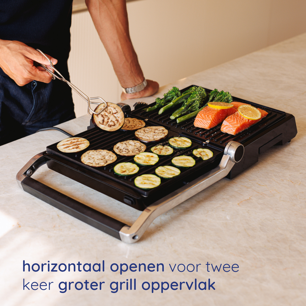 A person uses tongs to remove cooked food from a grill. Vegetables and salmon are on the grill. A person is in the background.