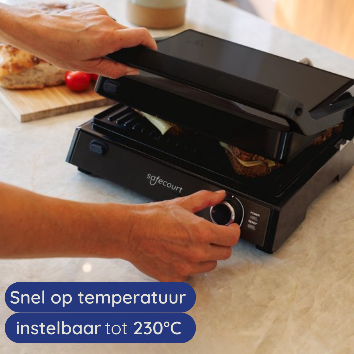 Hands adjust the temperature dial on a black grill. A sandwich is inside. Other food items are visible.