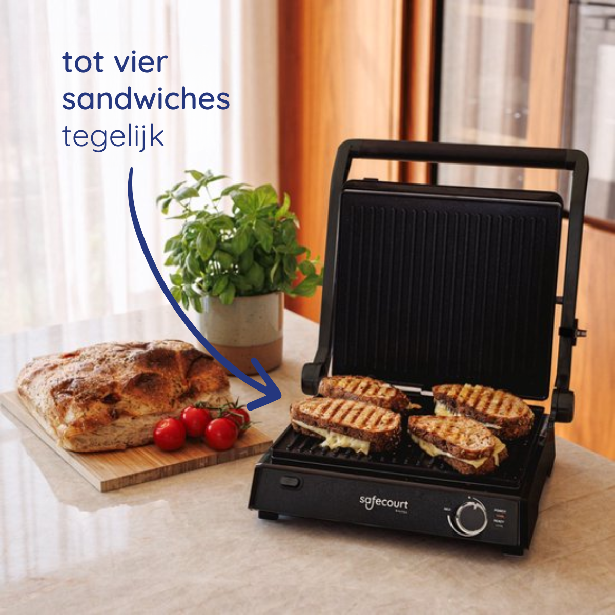 Sandwich maker with four sandwiches, bread, tomatoes, and a plant on a counter, promoting the ability to cook multiple sandwiches.