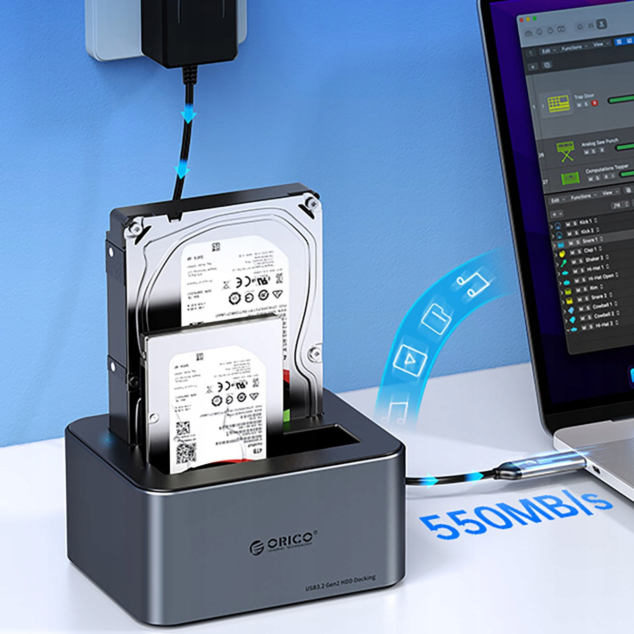 Dyski twarde włożone do szarej stacji dokującej, podłączone do laptopa. Prędkość: 550MB/s. Niebieskie akcenty.