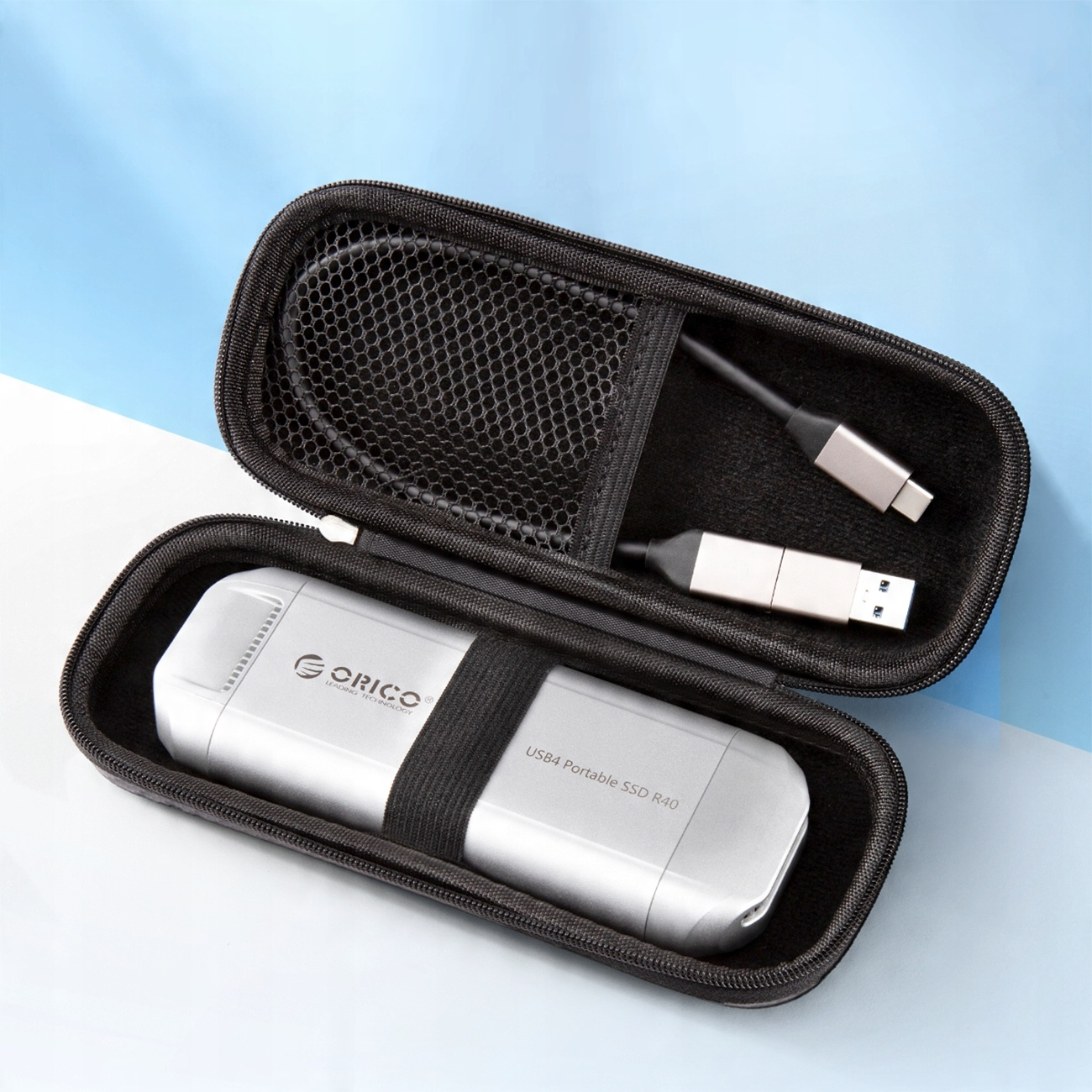 Otwarta czarna obudowa z srebrnym dyskiem SSD i czarnym kablem.