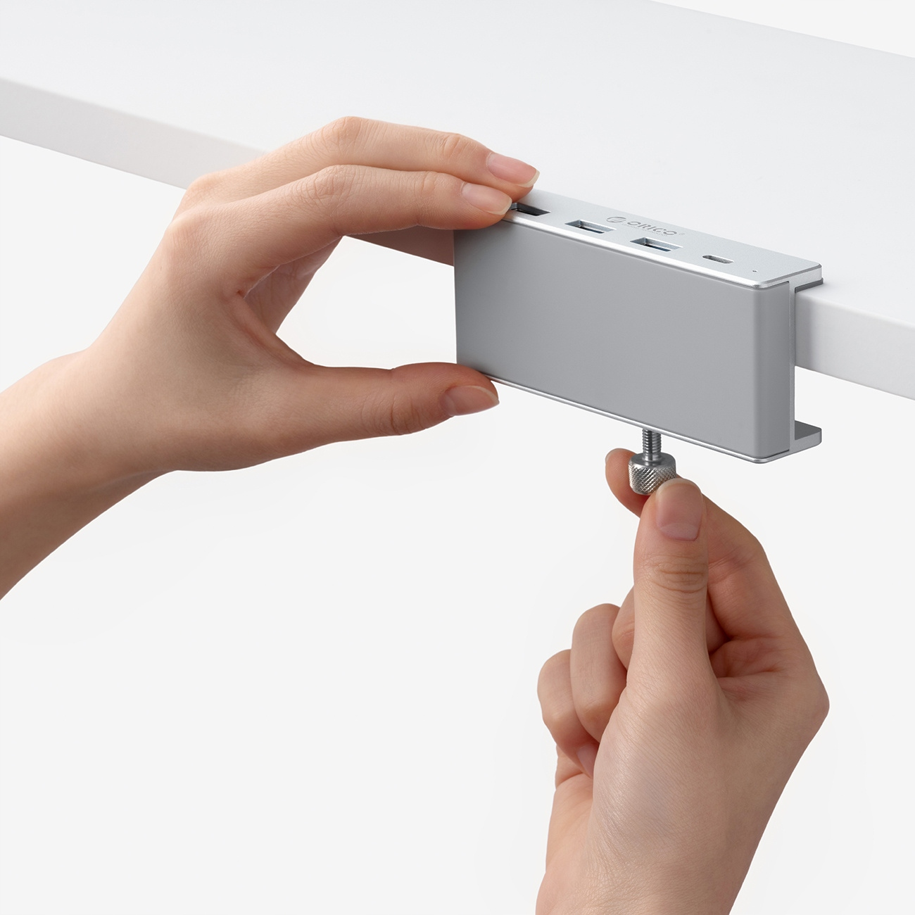 Ręce instalują srebrny hub USB na spodzie półki.