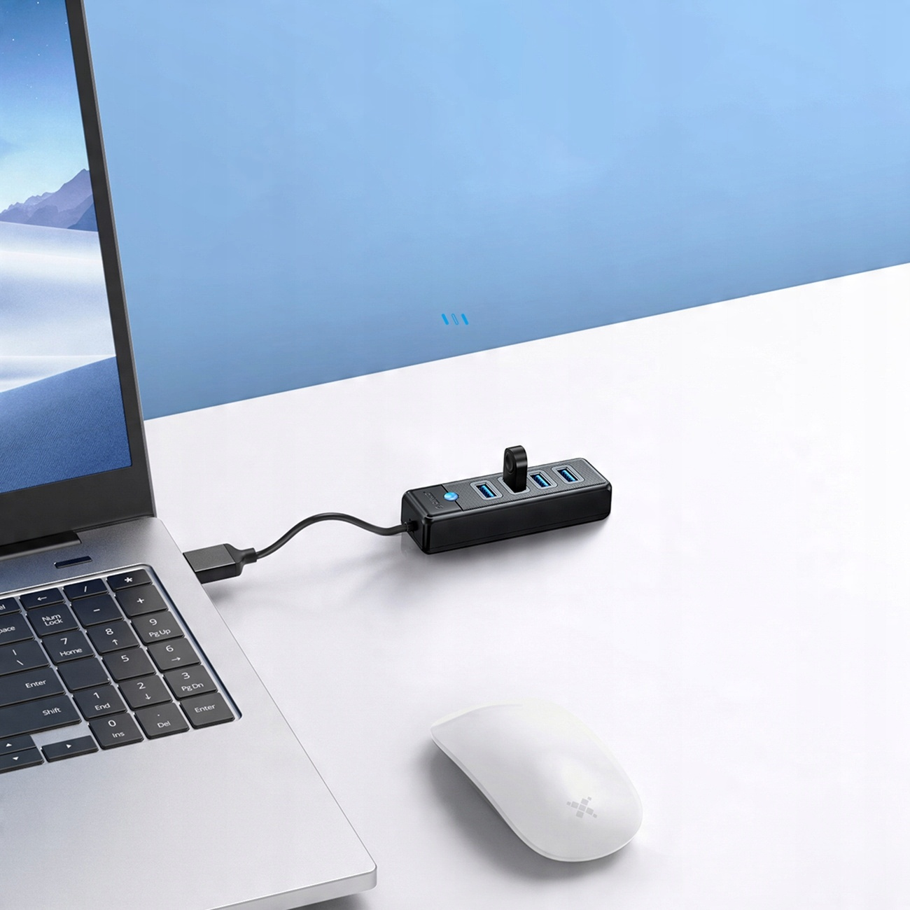 Laptop z hubem USB i myszką. Hub jest podłączony do laptopa i ma kilka portów.