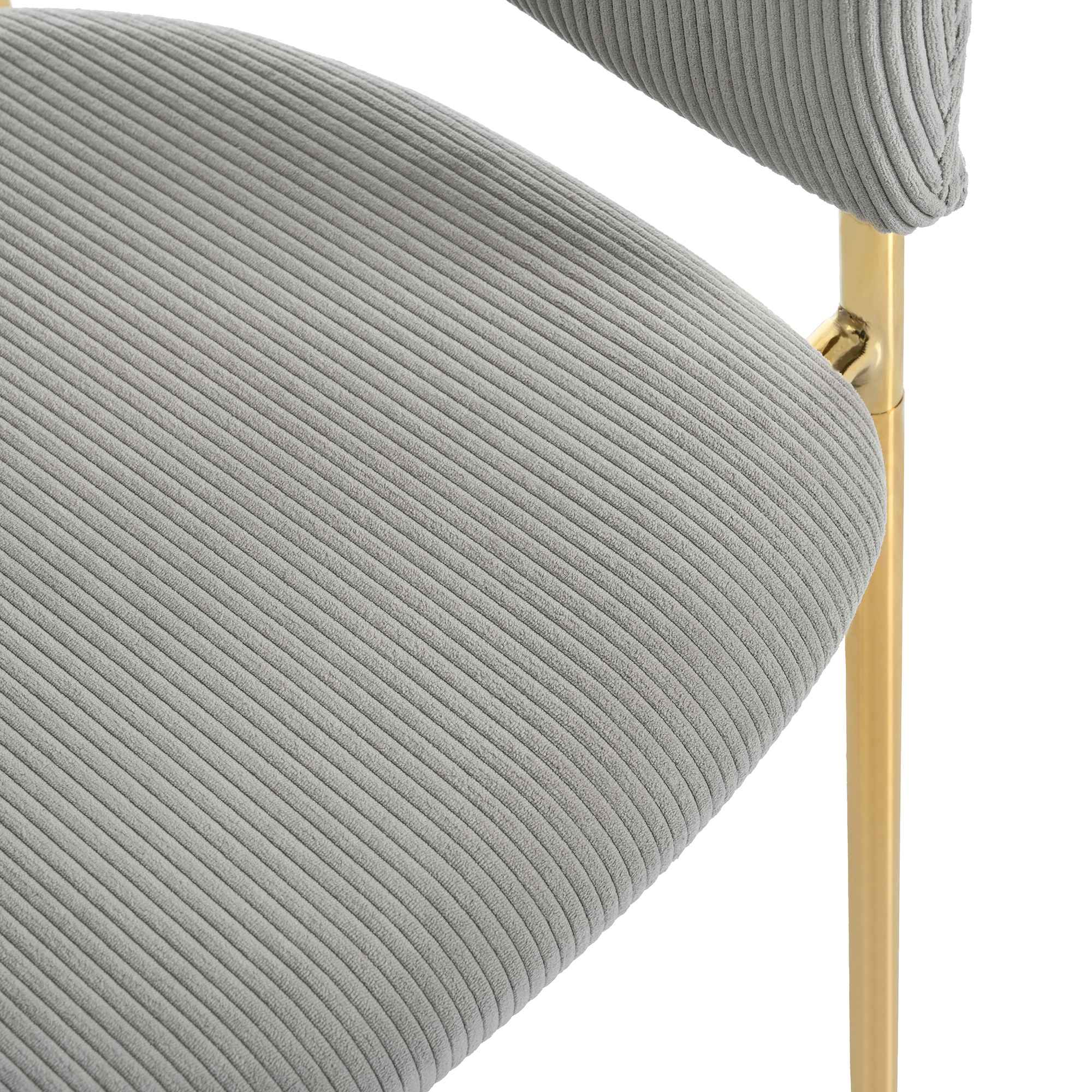 Nahaufnahme eines grauen Cord-Stuhlsitzes mit goldfarbenem Metallrahmen.
